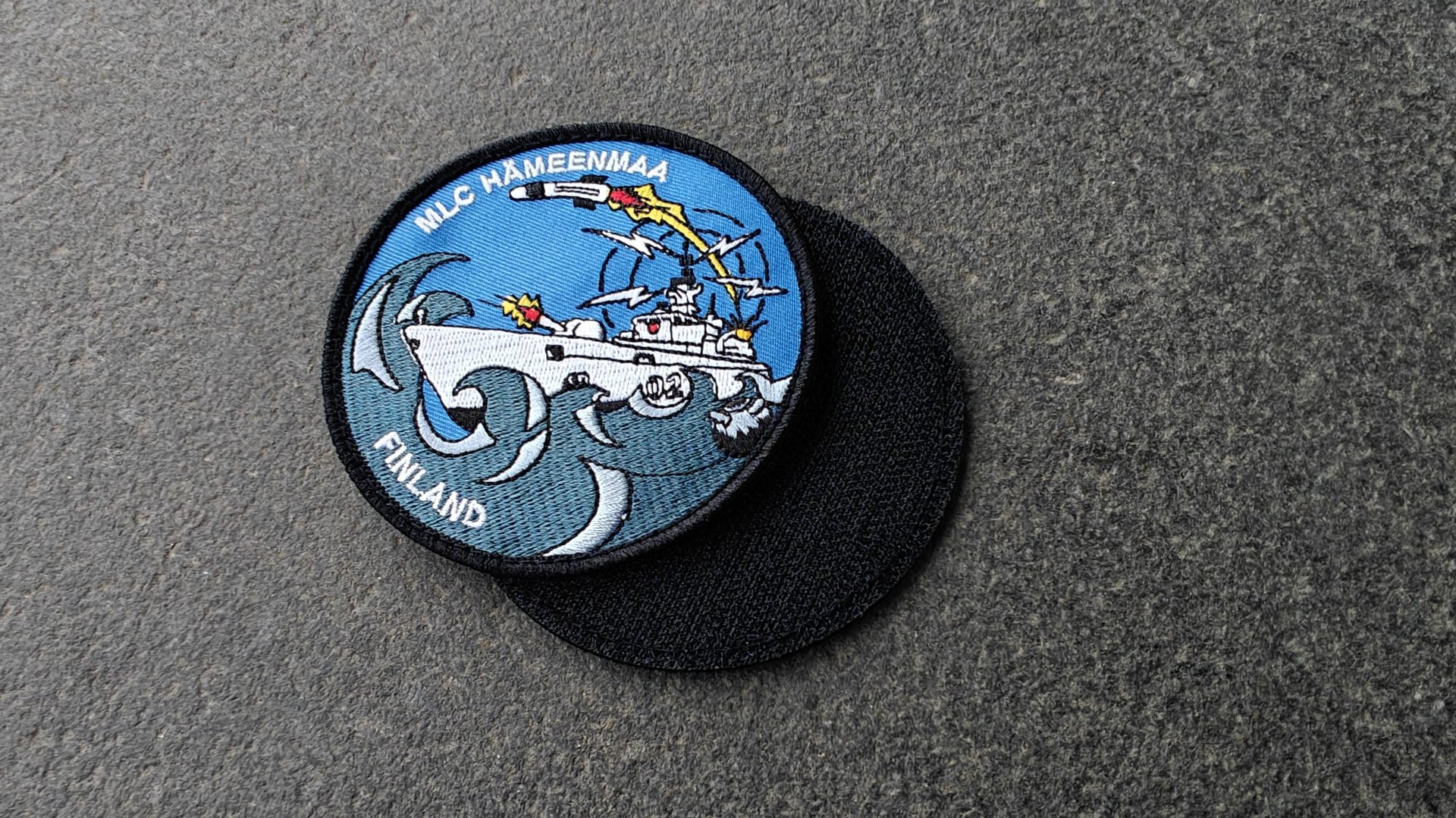 Colorful patch featuring a naval ship, waves, and a dolphin. Text reads MLC Hämeenmaa Finland.