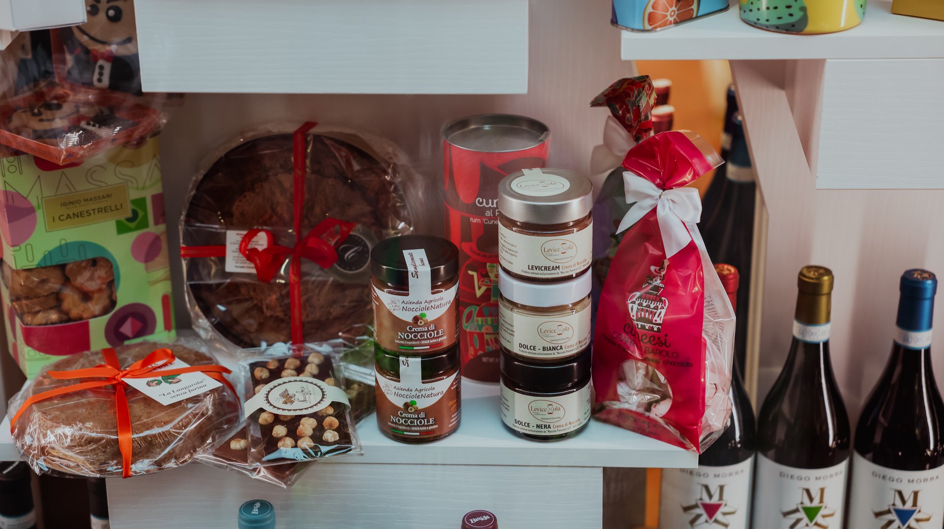Alba, Italy - October 27, 2024: A variety of local delicacies including baked goods and gourmet jars are showcased on a shelf in a shop in Alba, Italy, inviting visitors to explore regional flavors and culinary delights.