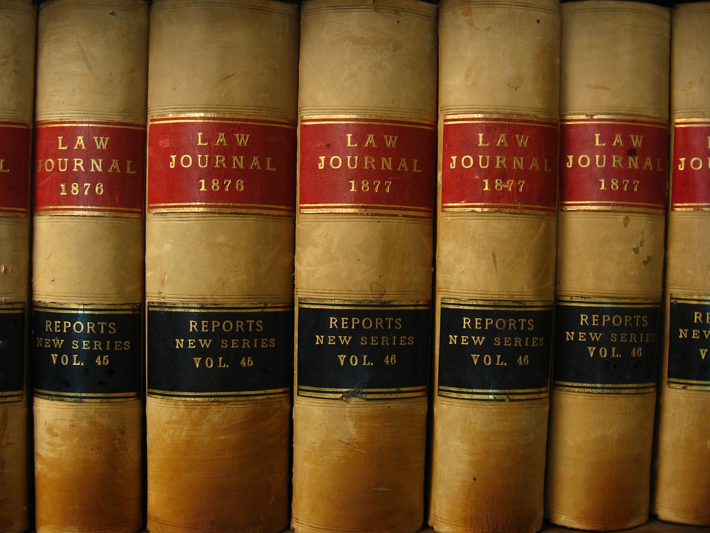 Close-up of vintage law journals and report volumes from 1876-1877 with red and black spines.