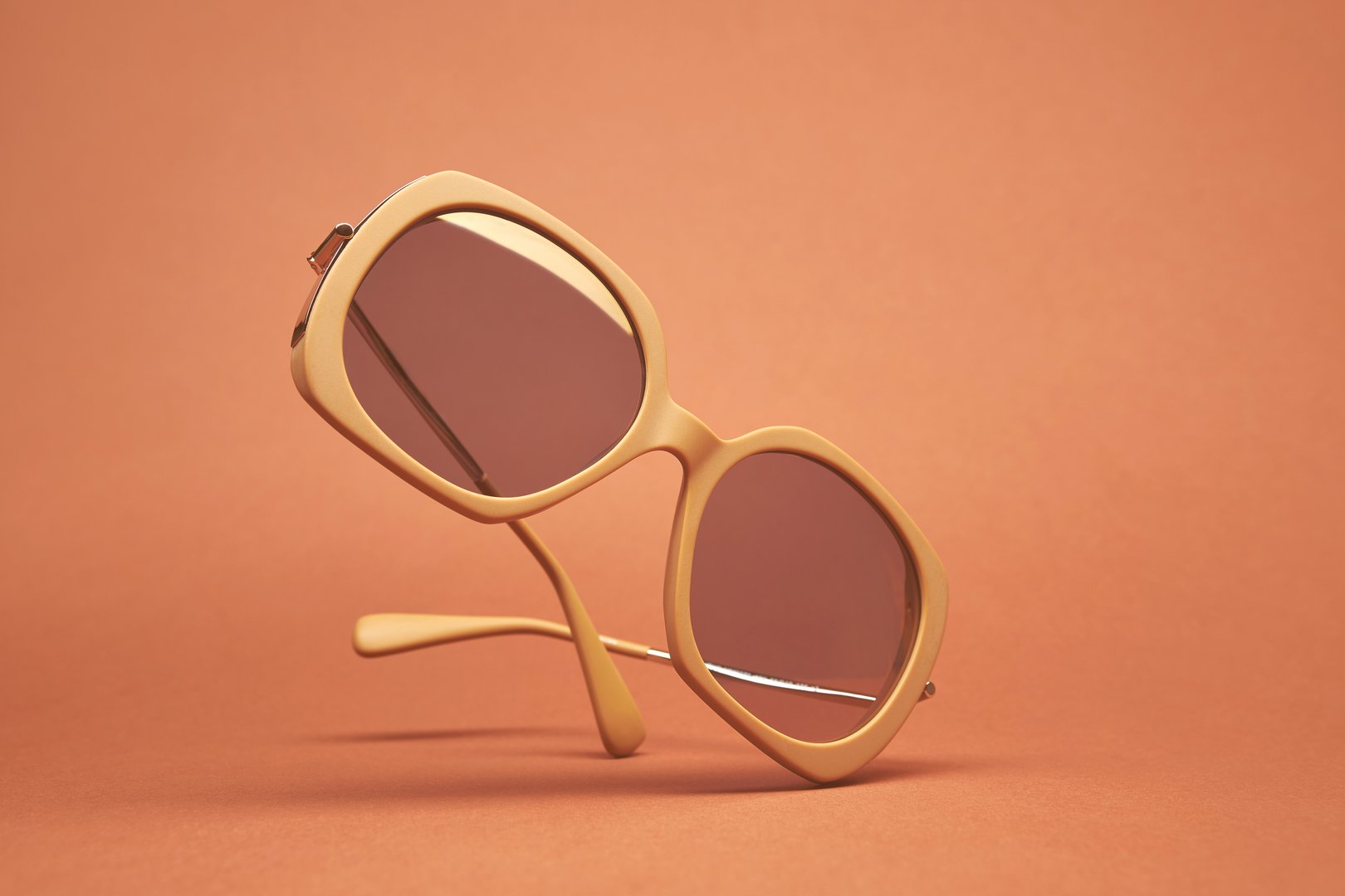 Fashionable sunglass with beige frame color isolated on the bright solid fond plain beige-pink-orange background, illustration eyewear concept