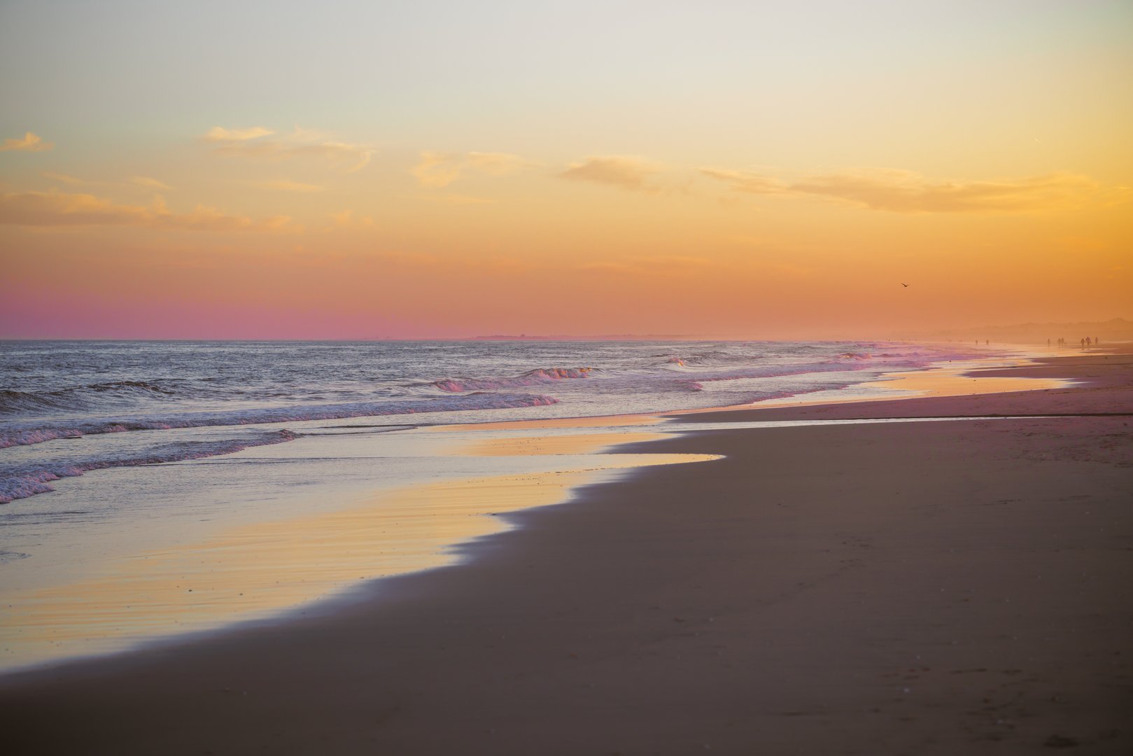 Sunset casts a warm glow over the serene beach scene.