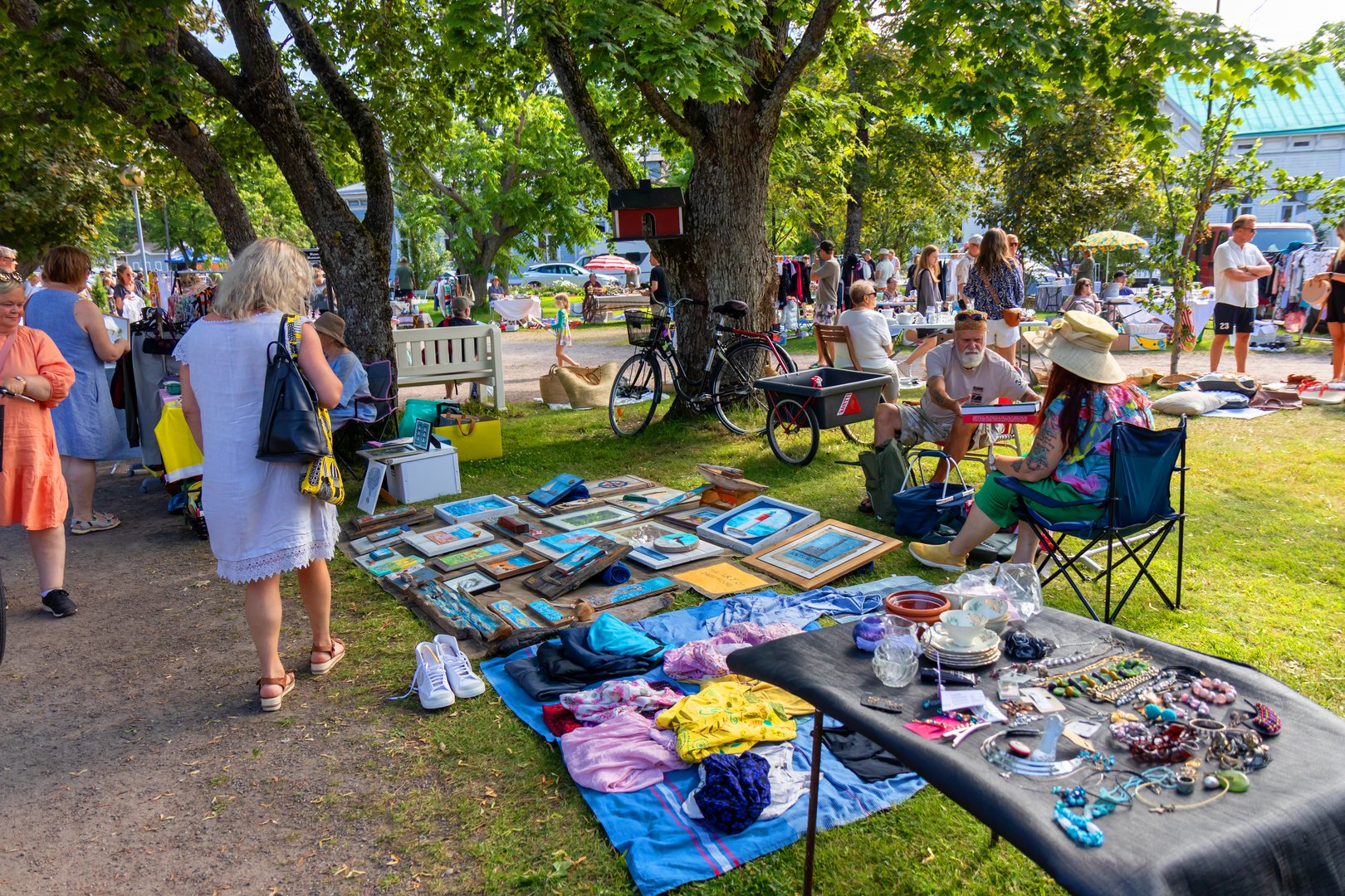 Hanko, Finland - July 31 2025: buyers browsing on a finnish street flea market named kirppis or loppis, tables filled with used old vintage things and clothes for sale. Reuse, second hand and eco consumer