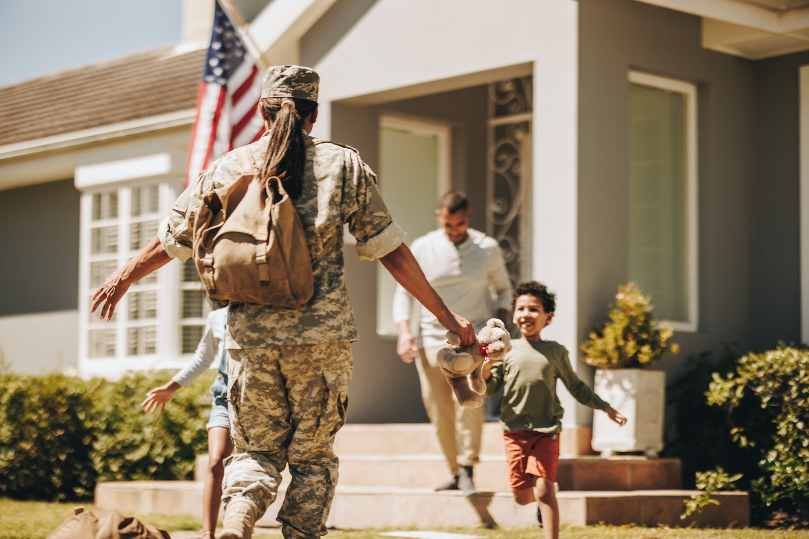 Female soldier reuniting with her family after serving in the army. American servicewoman receiving a warm welcome from her husband and kids. Military woman returning home from deployment.