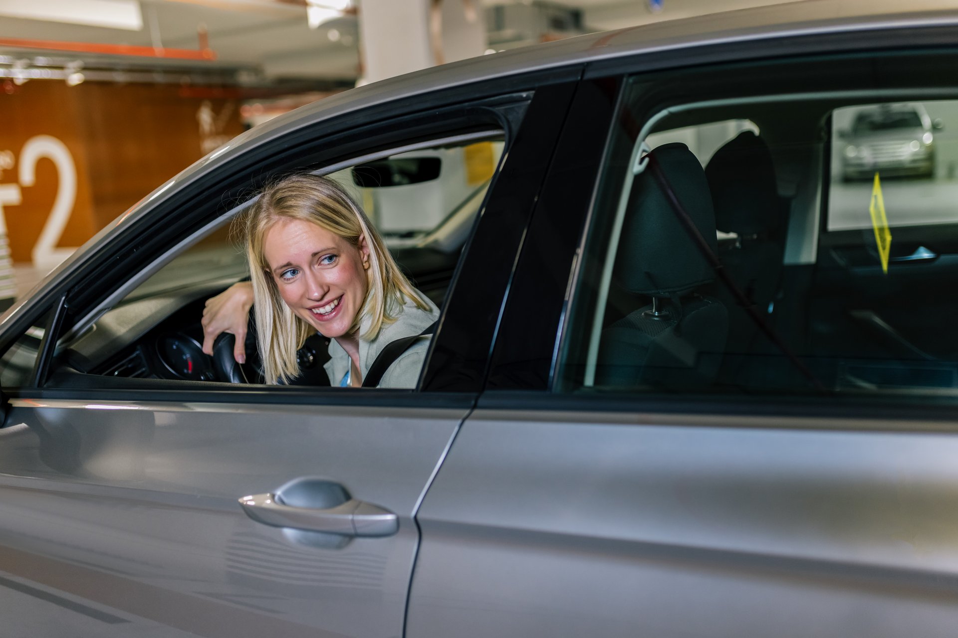Blonde woman parking in reverse in a underground garage.