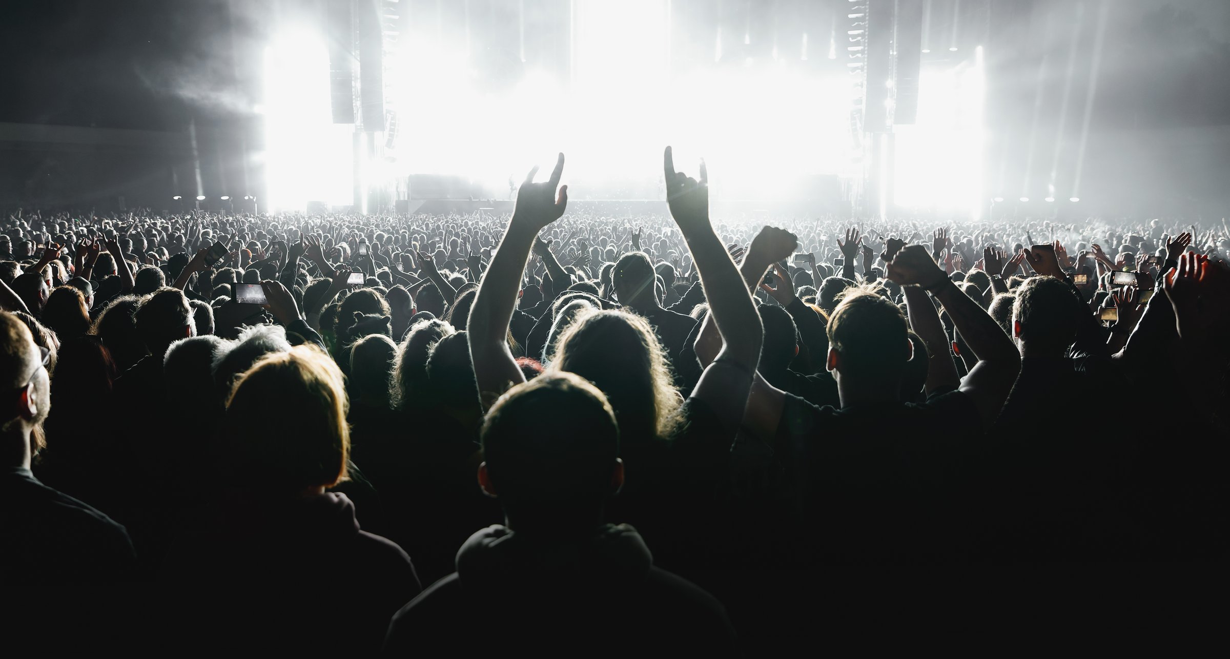 A lot of people raised up hands at the concert event. Fans arms against the stage light