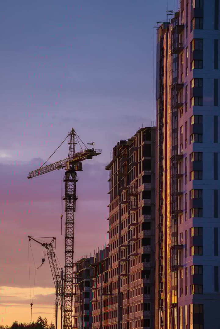 Tower cranes working on a new residential building construction project at sunset, showcasing urban development and the progress of modern architecture