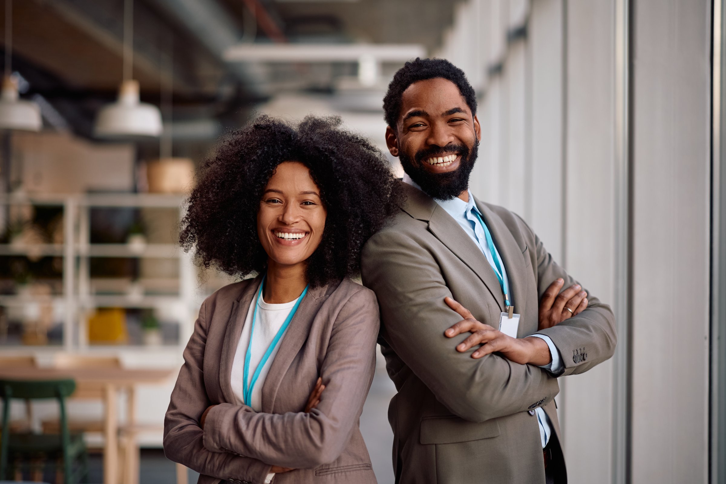 Confident African American entrepreneurs standing with crossed arms in the office and looking at camera.