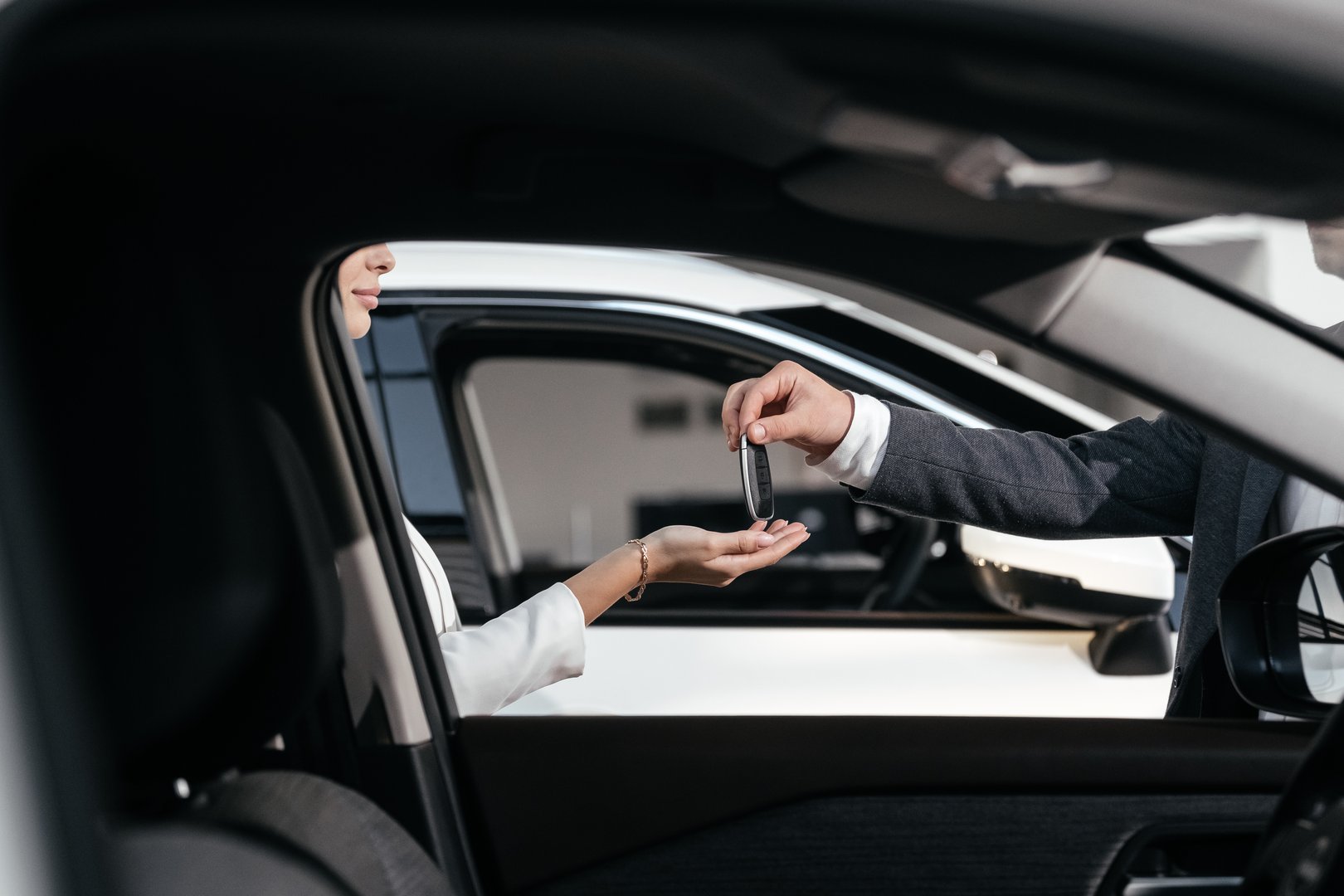 A close-up of key handover at a car dealership. This moment highlights the culmination of an expensive purchase, symbolizing a new life with the car and a touch of luxury.