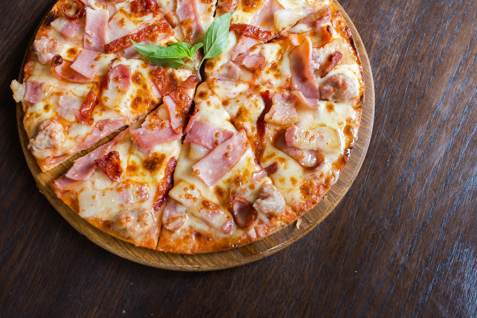 Rustic pizza with ham, sausage, mushrooms, and corn