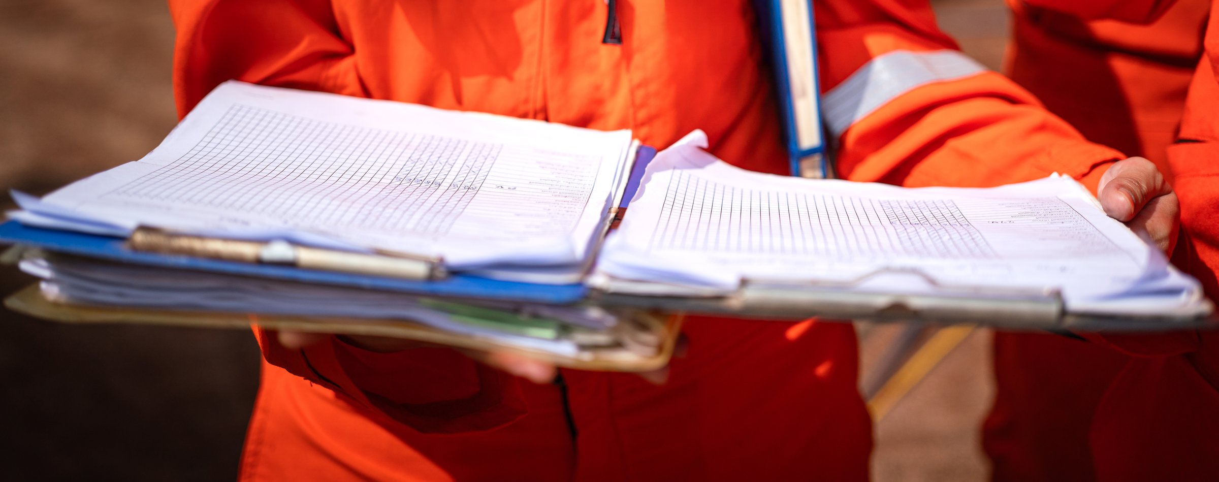 Action of a safety supervisor is review on the document paperwork during perform safety audit with background of the industrial worksite. Close-up and selective focus.