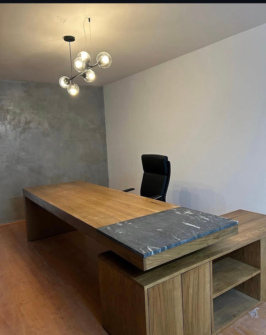Escritorio direccional en madera con cubierta amplia, detalle de placa de piedra natural y diseño en L con credenza