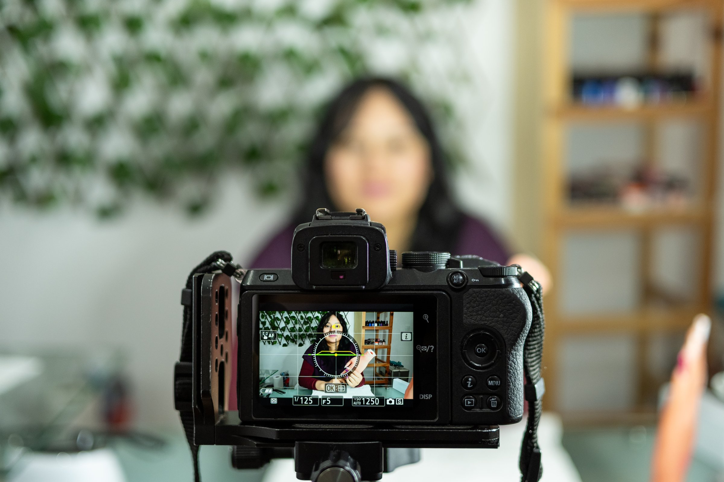 Young latina woman using a professional camera to record a video course