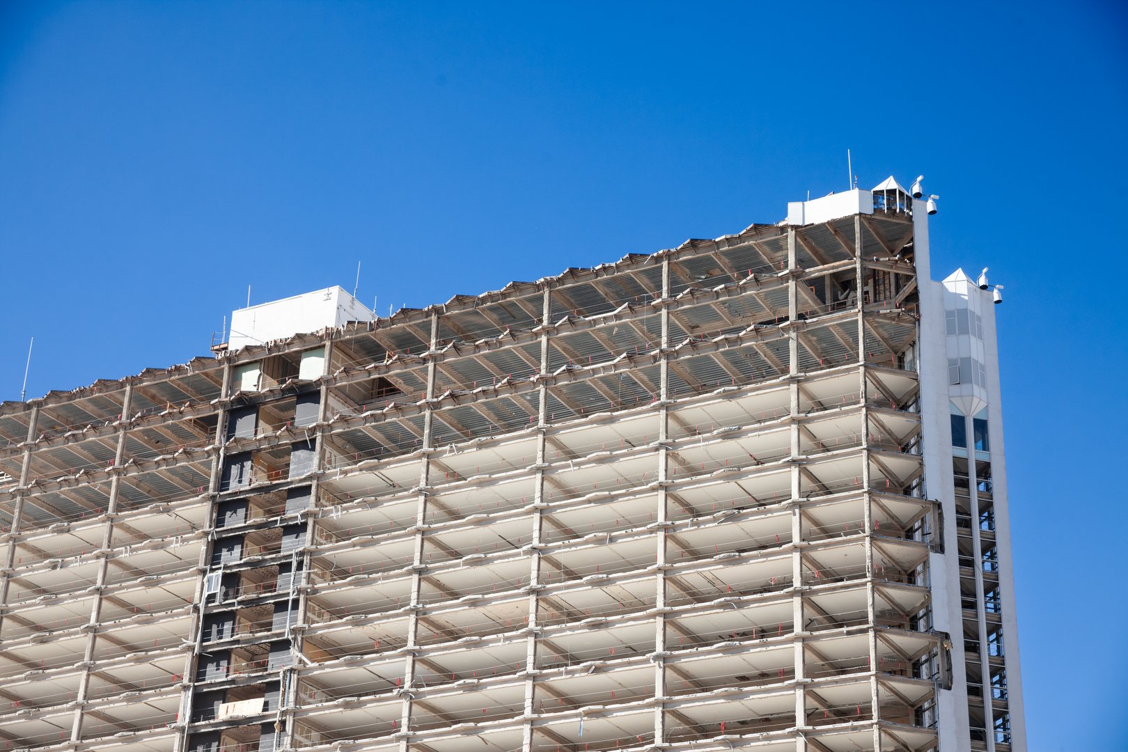 The image depicts an active demolition site in Las Vegas, where heavy machinery works to dismantle an old building. Dust and debris fill the air as the structure is taken apart, signaling the end of one chapter and the beginning of another in the city's ever-changing landscape. This scene highlights the bustling demolition industry in the USA, a crucial aspect of urban redevelopment and economic progress. The photograph emphasizes the transformative nature of cities like Las Vegas, known for their rapid growth and constant reinvention. It touches on themes of modernization, the lifecycle of urban architecture, and the impact of construction on the environment. The visual contrasts between the remnants of the old building and the anticipation of new developments offer a compelling narrative about change and progress in urban settings.