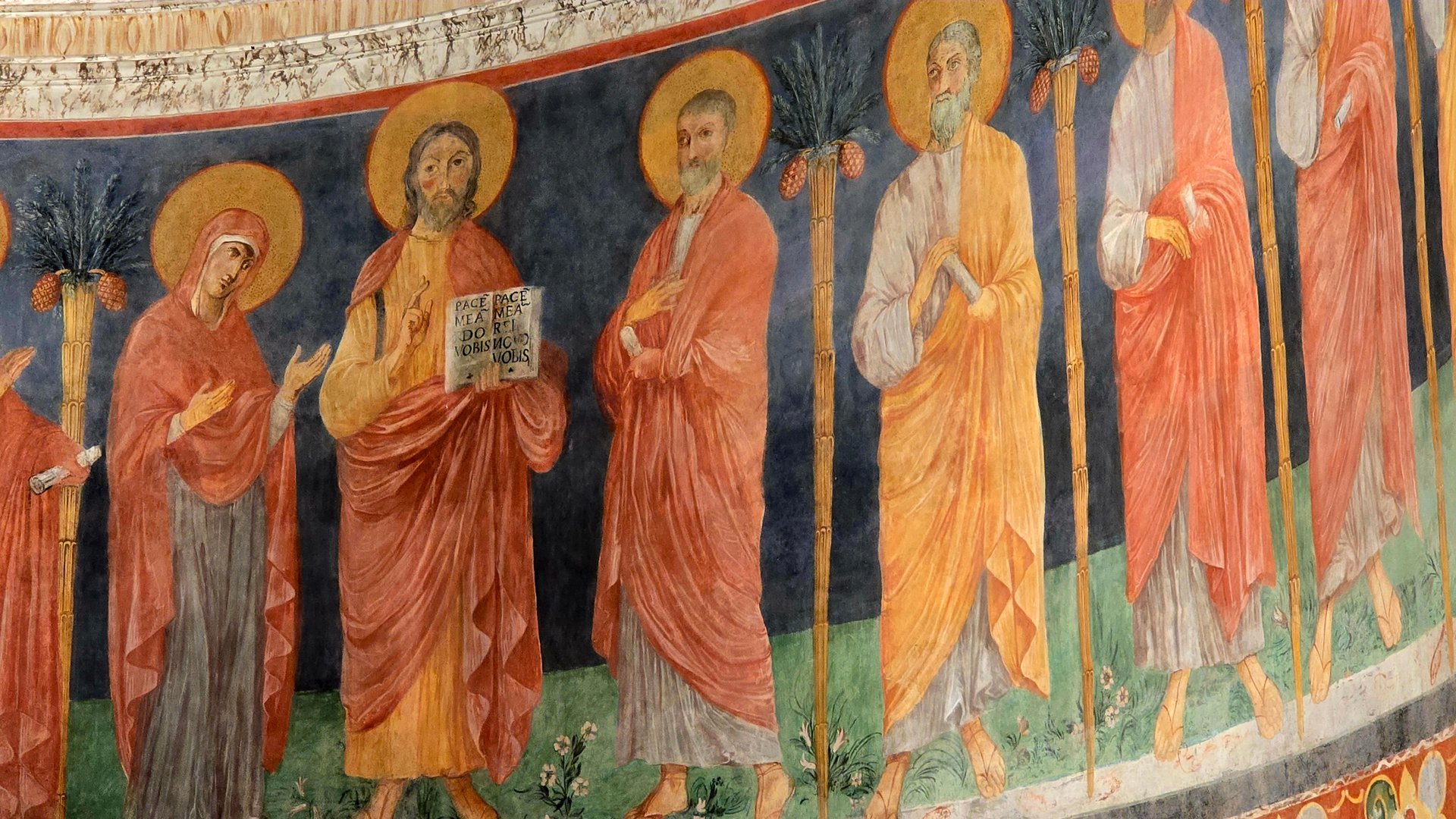 Rome, Italy - 11 January 2025. Fresco detail from the apse of San Clemente showing Christ with a Latin book, the Virgin Mary, and apostles in red and gold robes beneath palm tree motifs.