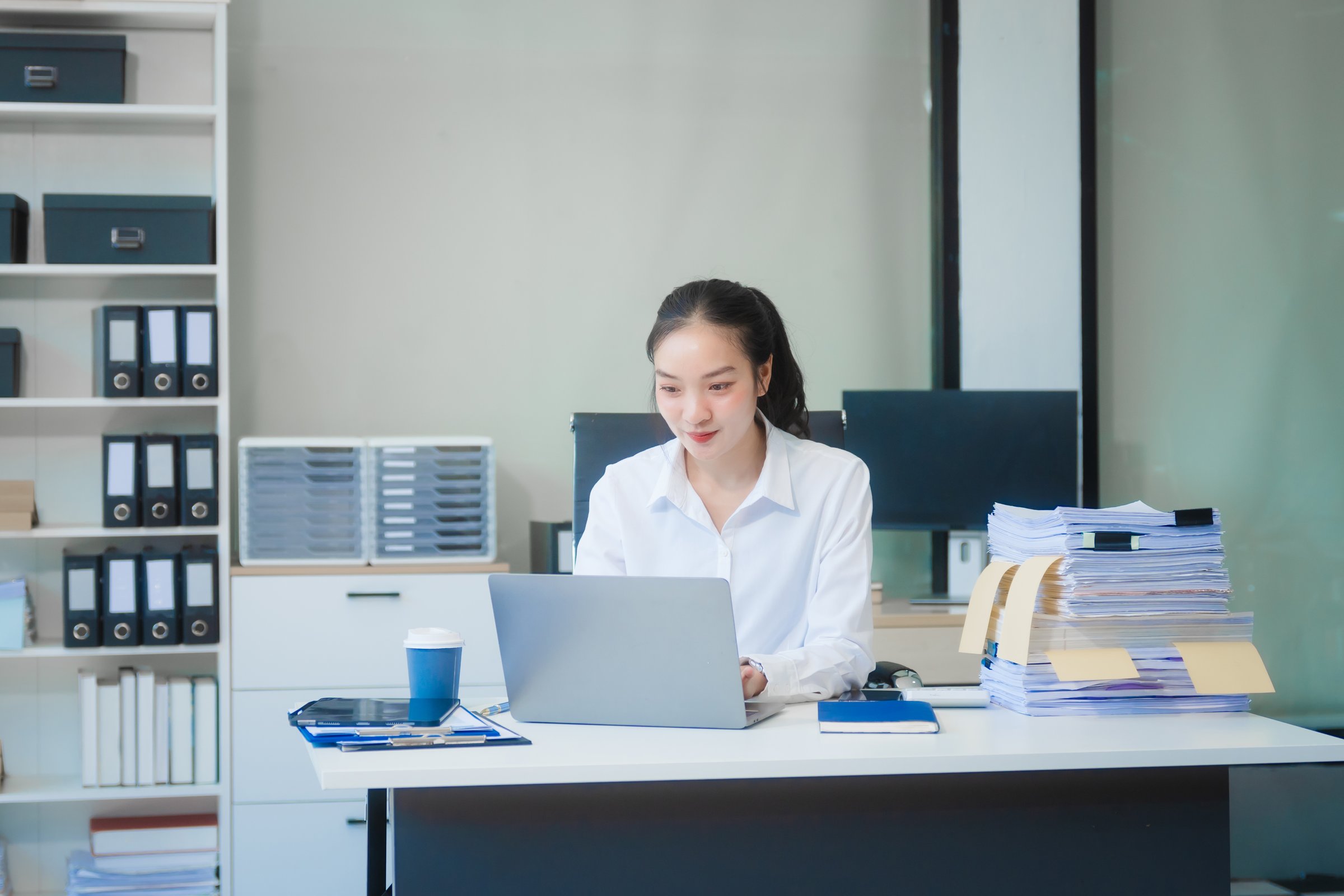 Young Asian businesswoman works at desk with laptop and financial documents