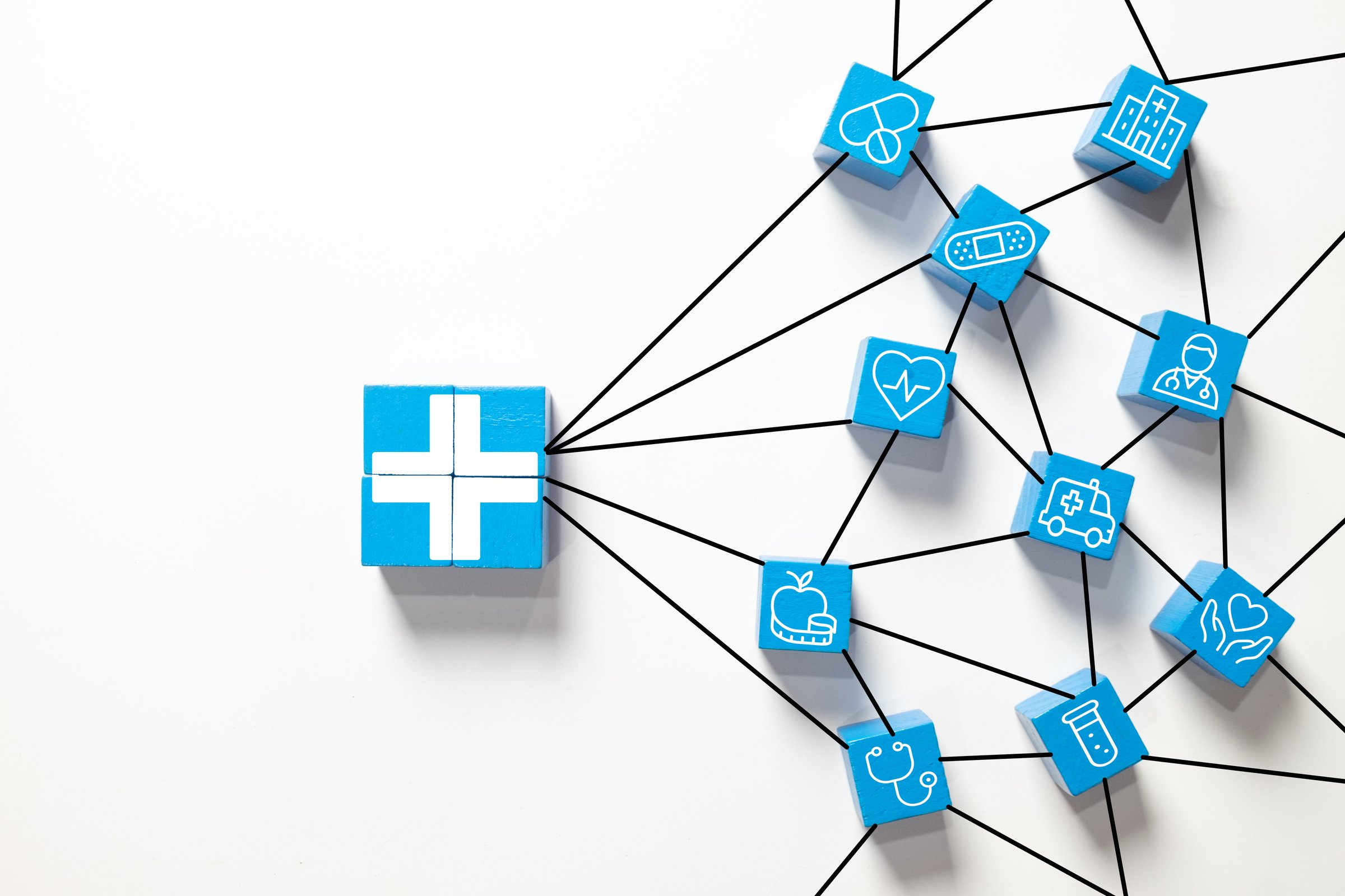 Healthcare network and medical insurance concept.A central cross symbol connected to various medical service icons on blue blocks, symbolizing a comprehensive hospital system,patient care,and safety.