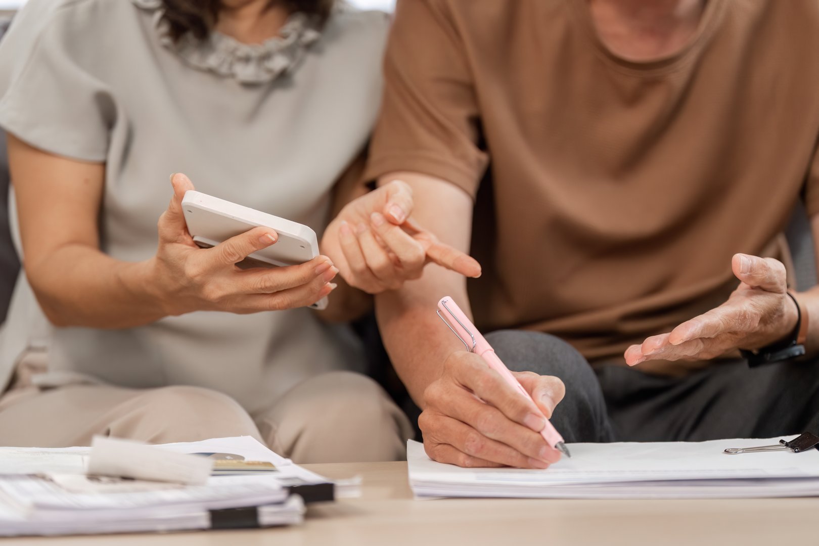 Senior couple working together on financial planning, using documents and a calculator to manage family finances.