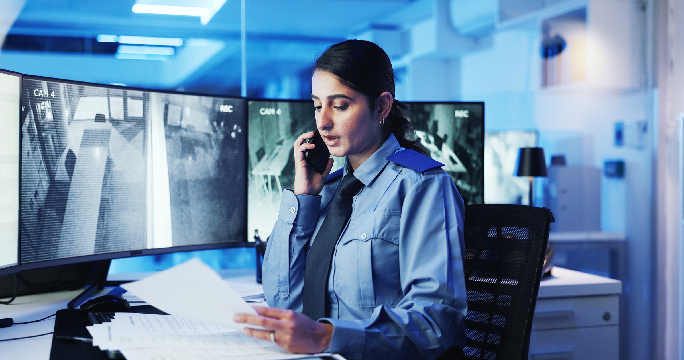 Security, control room and woman at computer screen with phone call, documents and contact. CCTV, surveillance and safety officer with night, communication and intelligence report at command center