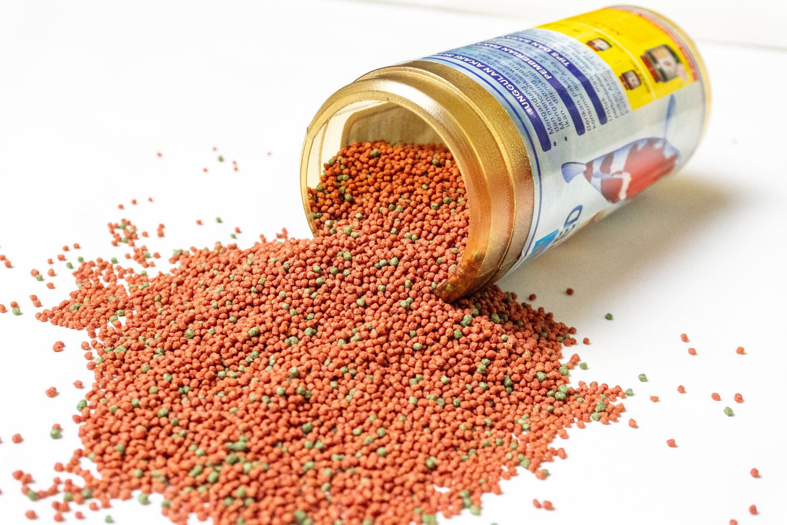 Red and green commercial fish food pellet caps are usually used for goldfish or aquarium fish food on white background.