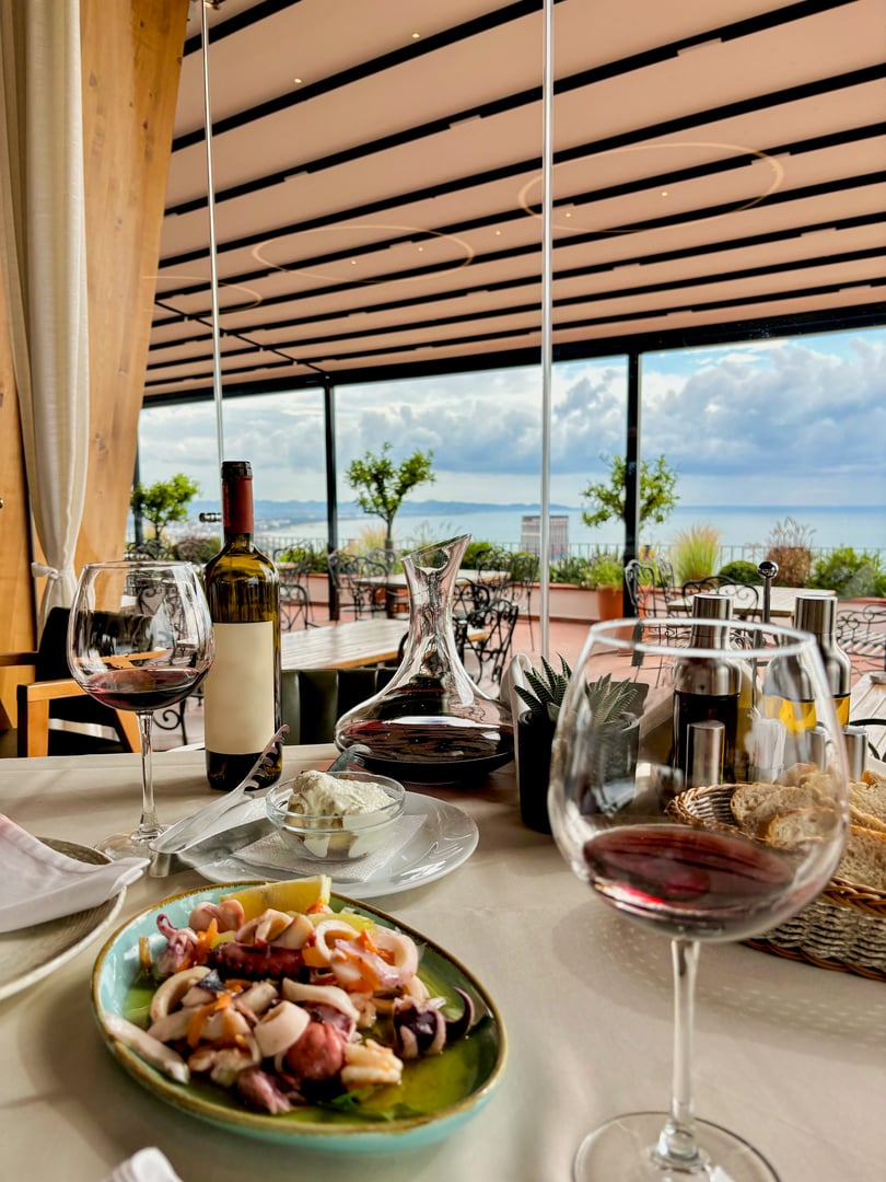 Restaurant by the sea with outdoor terrace, lunch by the sea, beautiful serving and serving with glasses and wine. High quality photo
