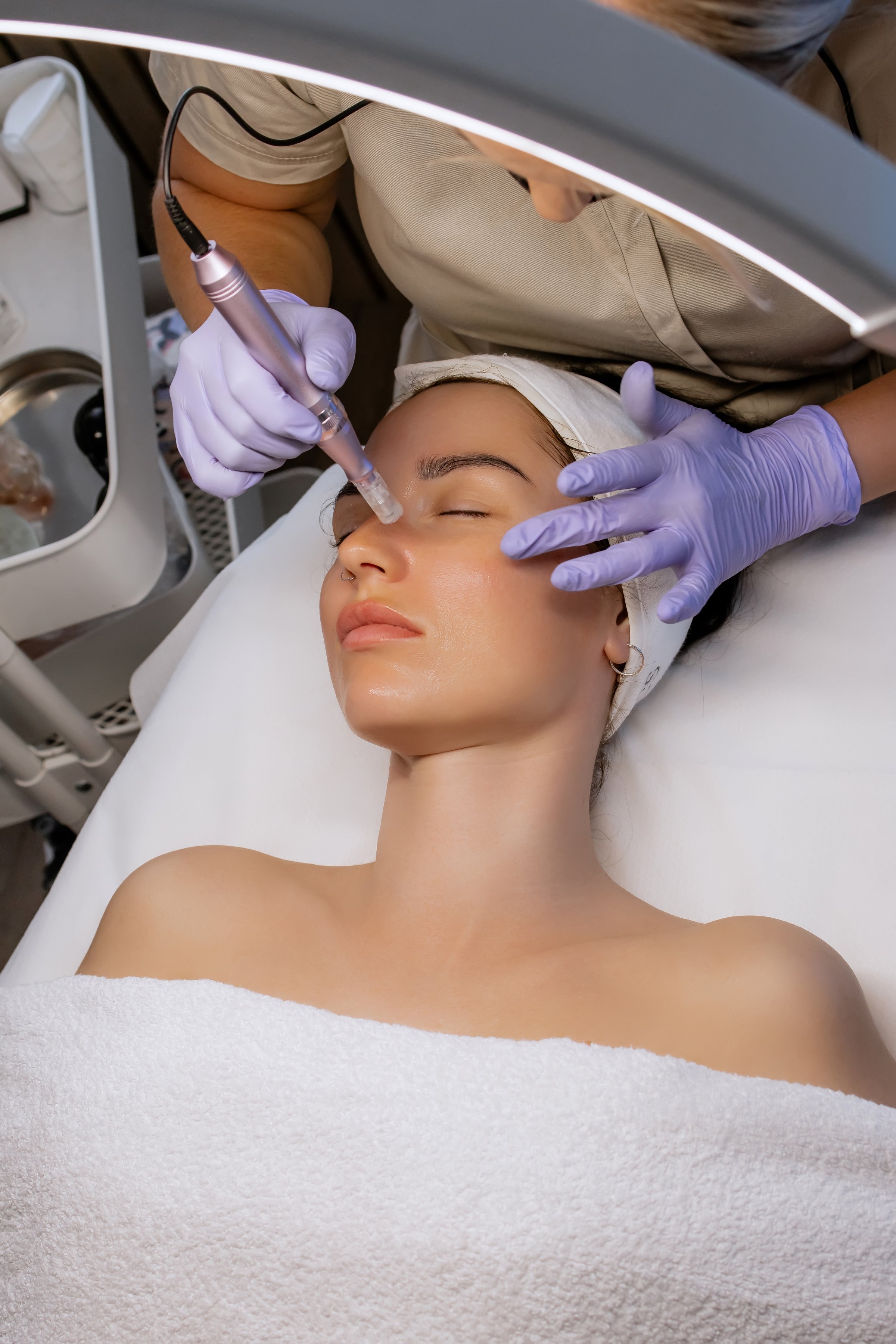 Woman receiving a professional microneedling treatment at a cosmetology clinic