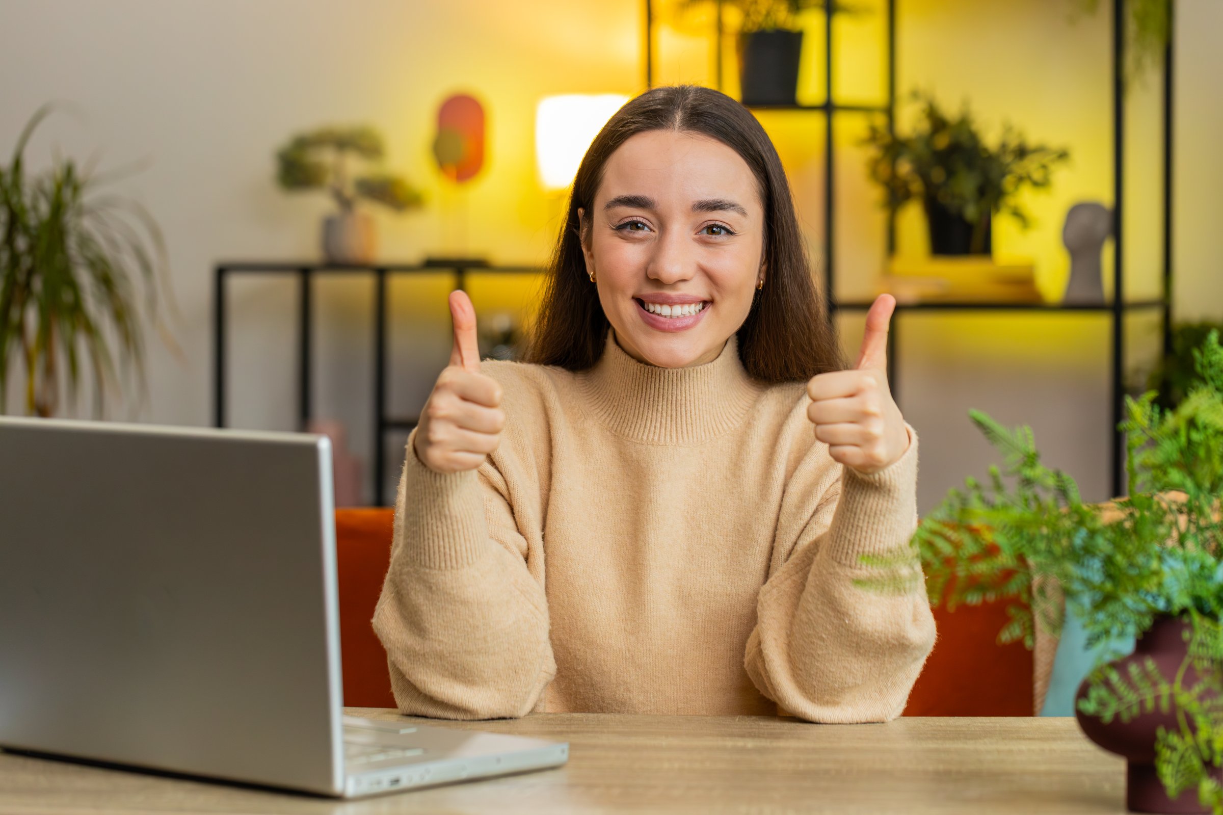 Like. Happy excited Caucasian woman looking approvingly at camera showing thumbs up like sign positive something good great news positive feedback. Young pretty girl sits at home office room at table