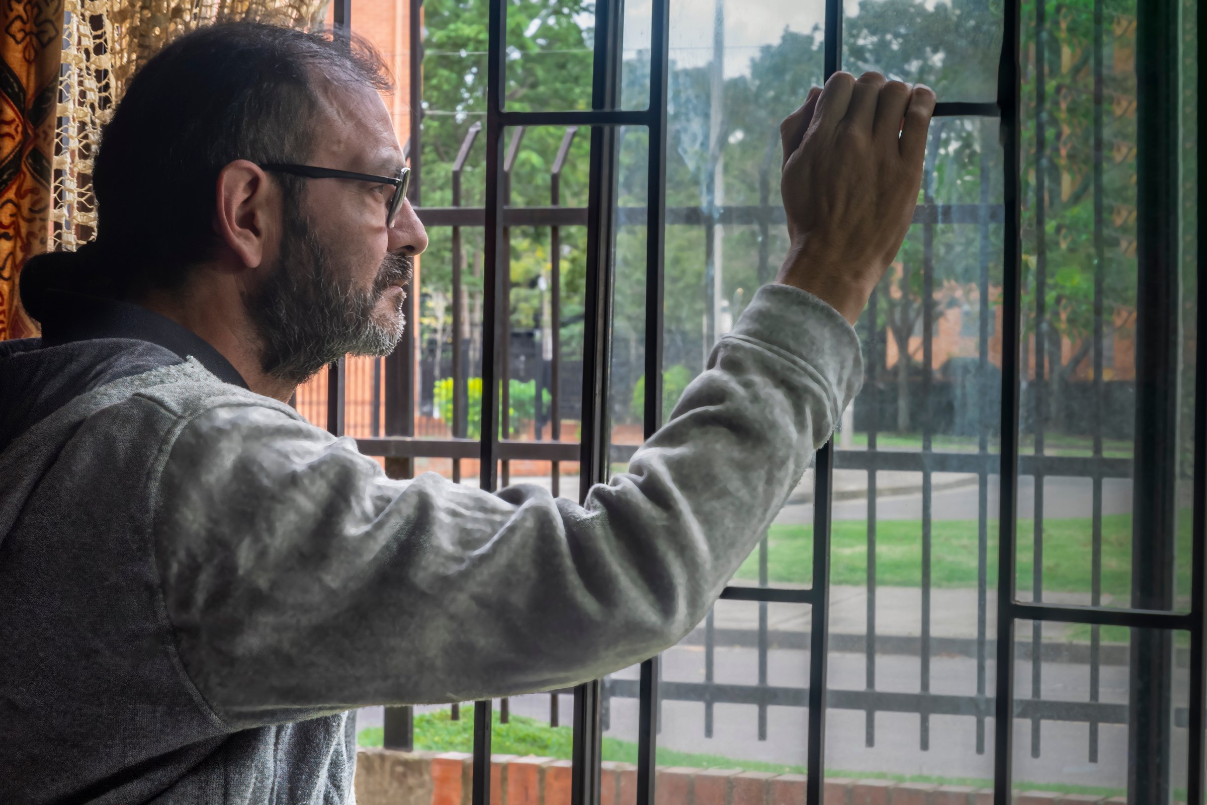 Older man looking out the window with a deep gaze