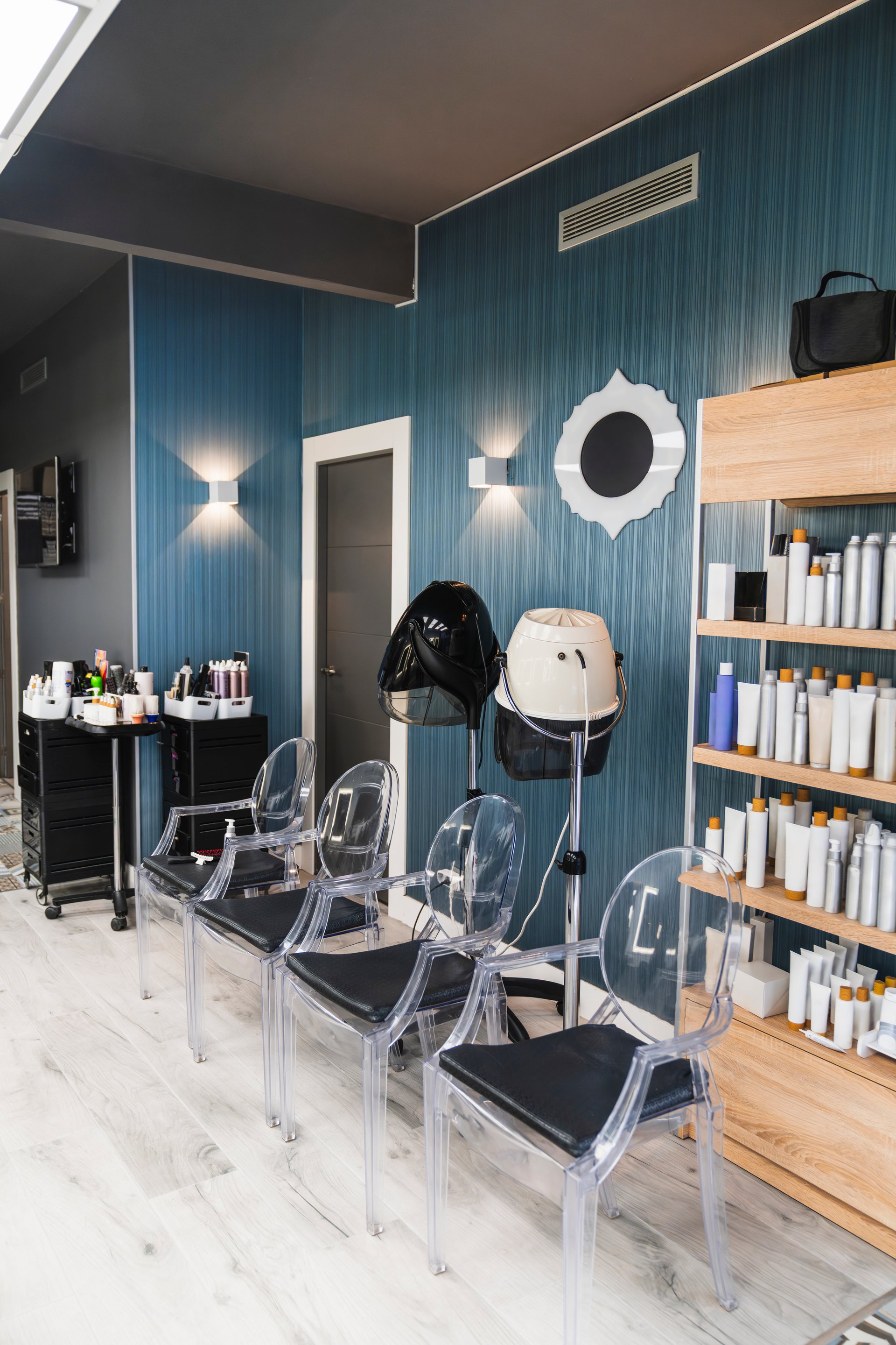 Empty interior of a modern hairdressing salon showcasing styling chairs, hair dryers, and shelves filled with various hair products