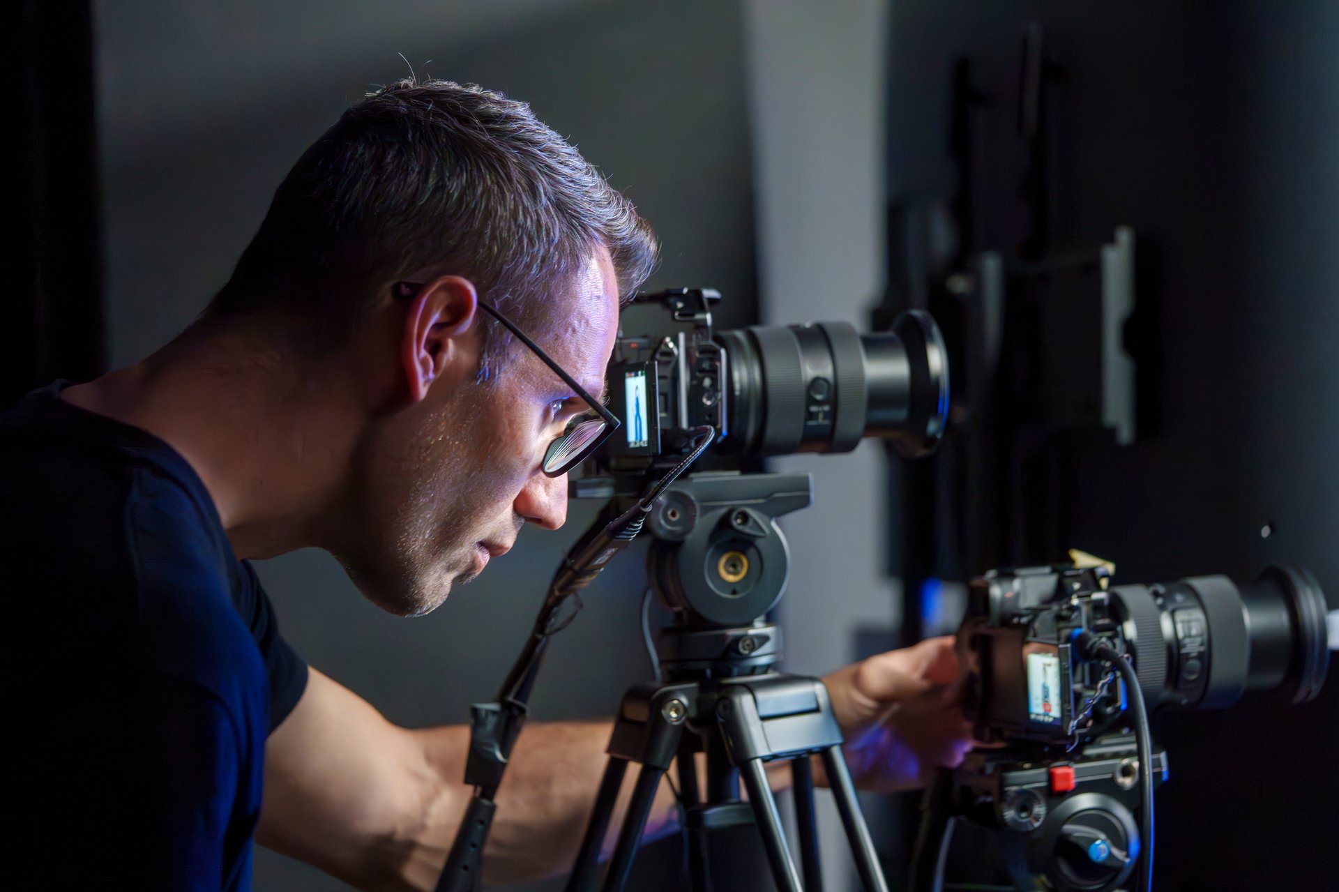 Mature Male Camera Operator Setting Up Cameras During a Live Broadcast in a TV Studio, Side View