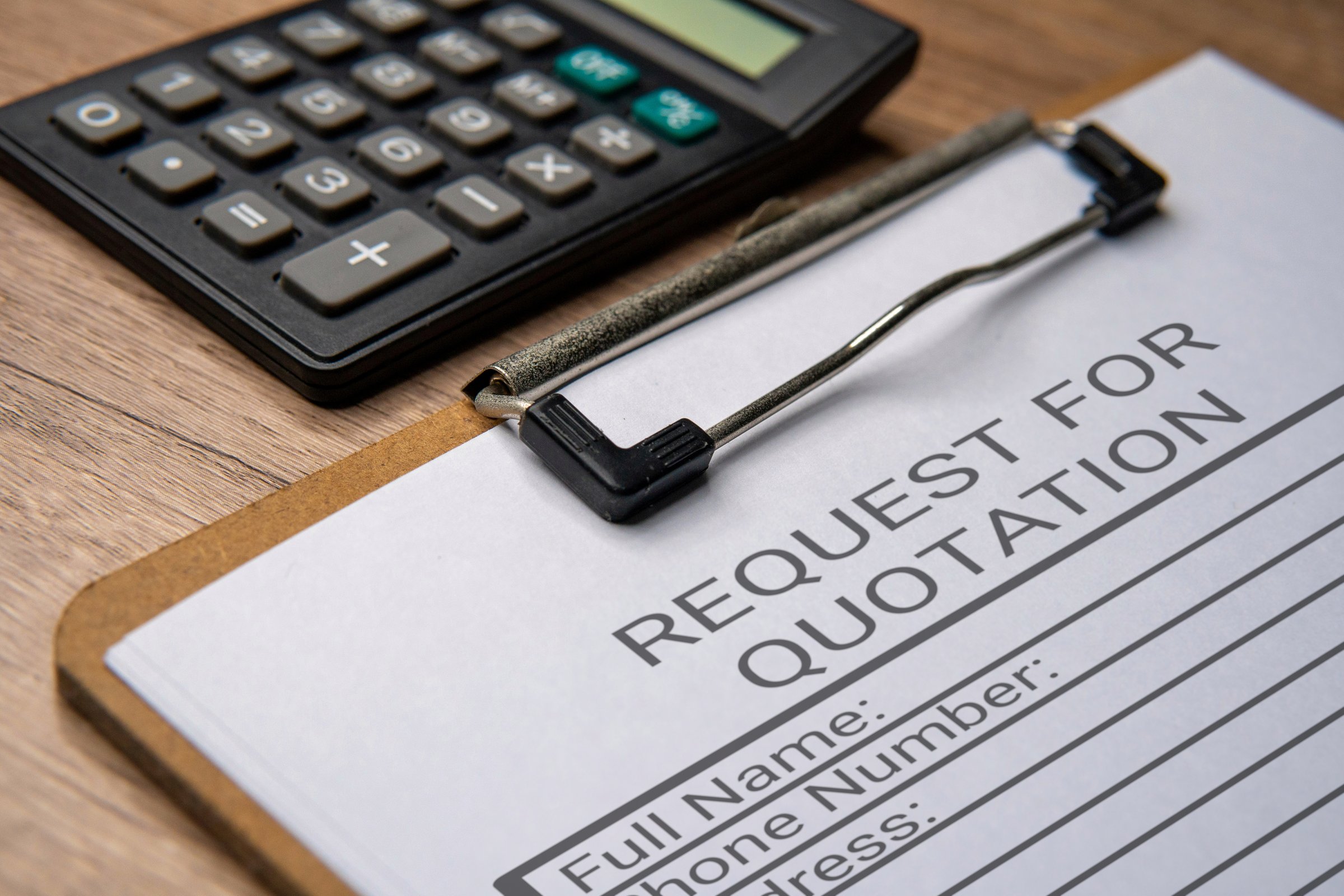 A clipboard with a paper titled REQUEST FOR QUOTATION and a black calculator