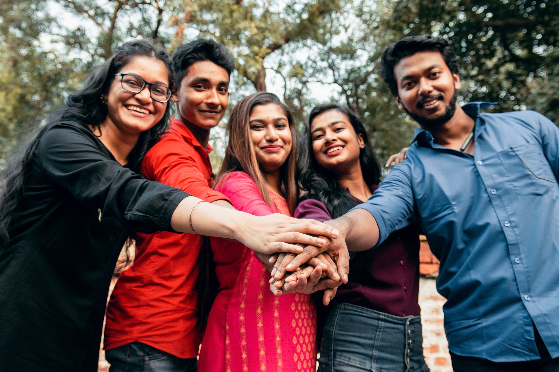 Close up top view of young people putting their hands together. Indian Friends with stack of hands showing unity and teamwork.