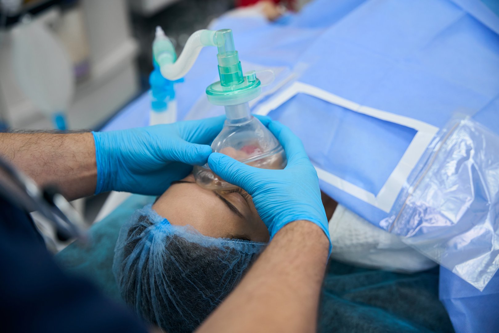Patient under anesthesia on the operating table, with an experienced anesthesiologist working with her