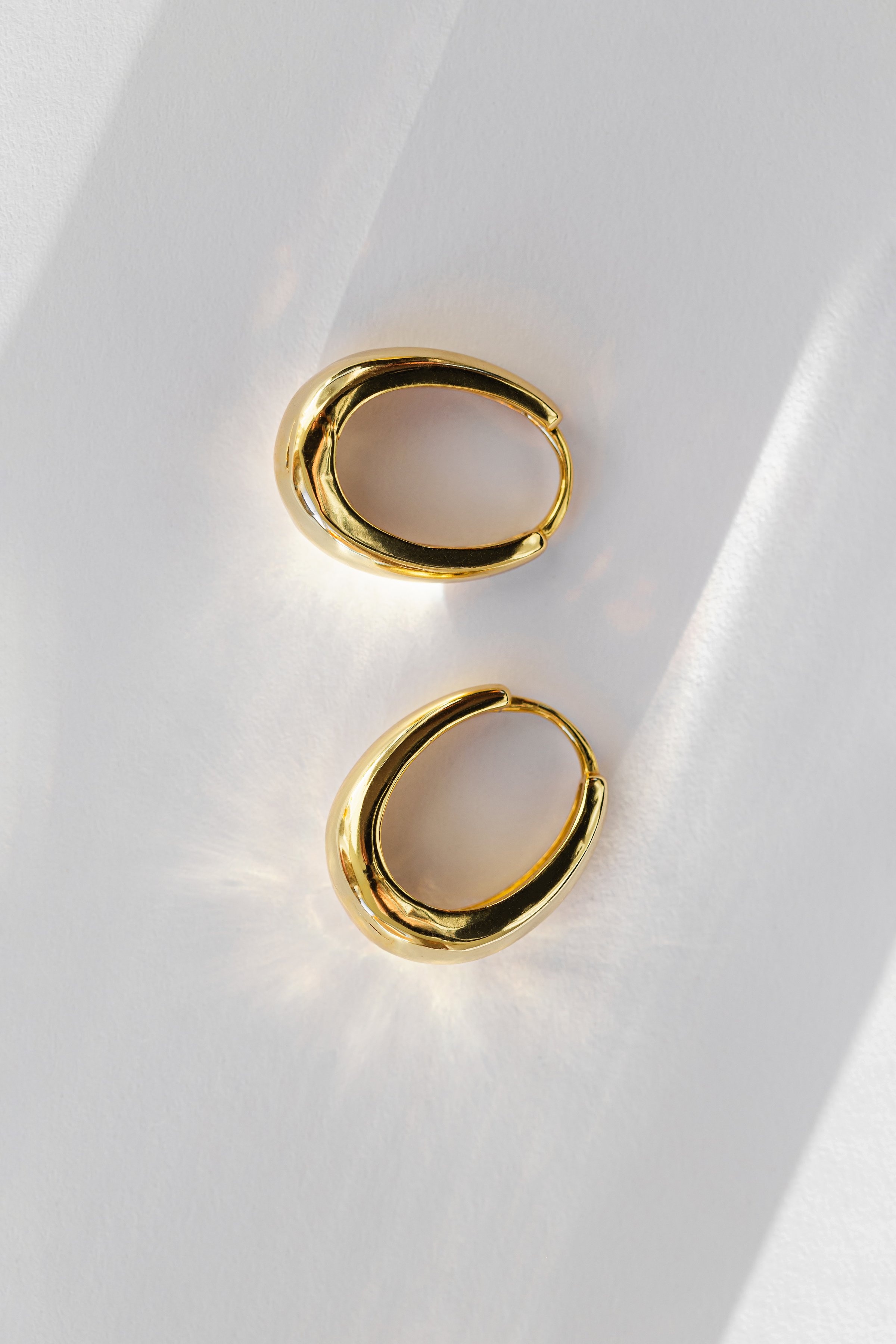 Gold earrings closeup on a white background with shadow. Concept of stylish women's accessories