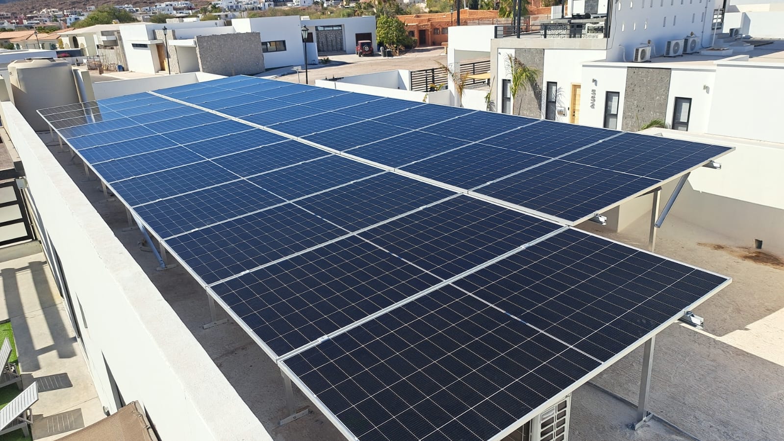 Large solar panel installation on a flat rooftop in a residential area with modern buildings in the background.