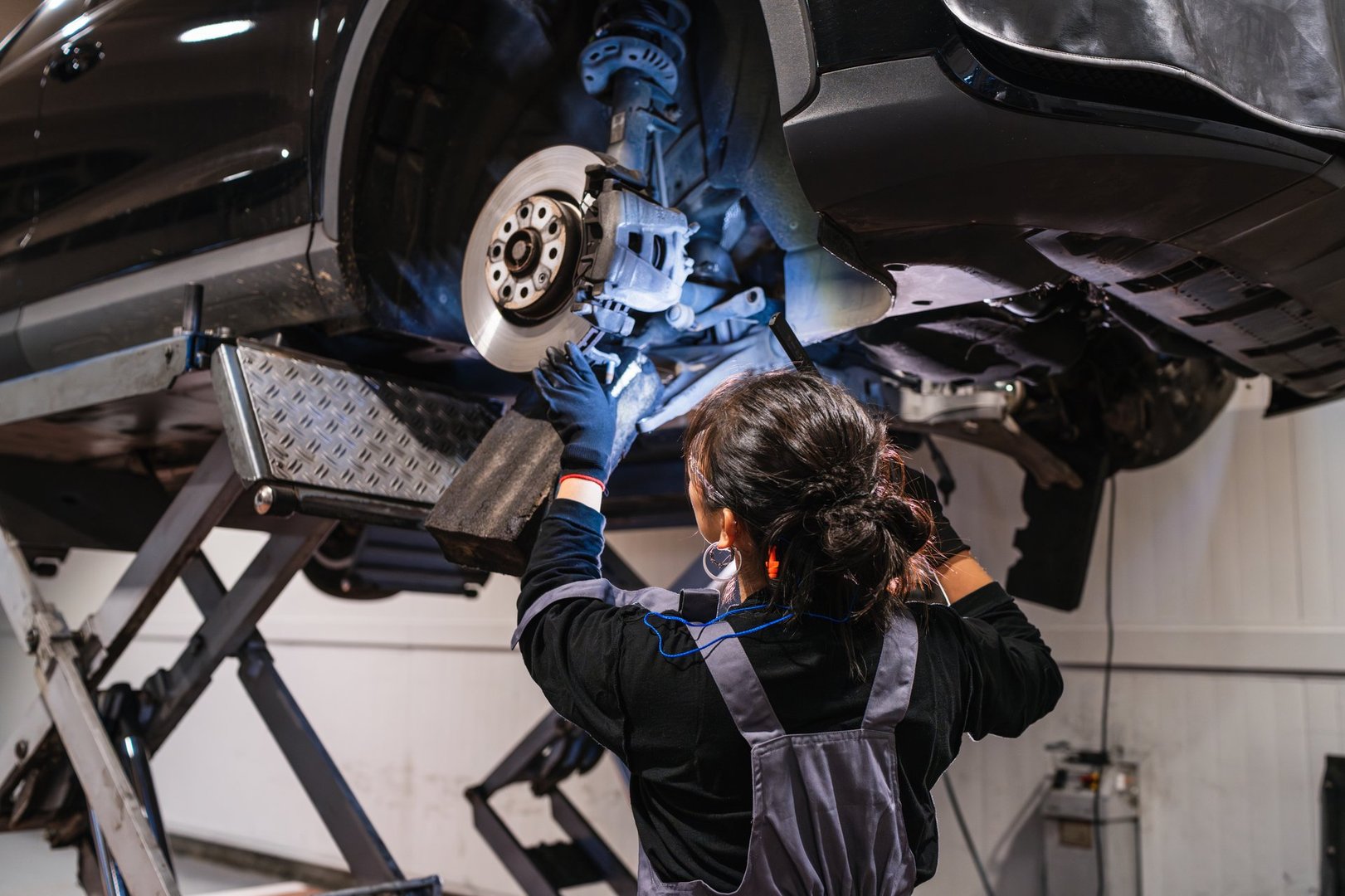 Mecánica trabajando debajo de automóvil elevado