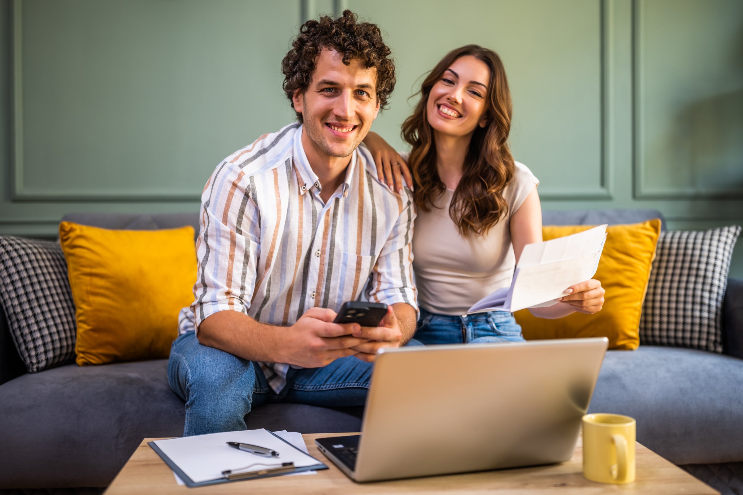 Couple discussing home finance while checking bills. They are checking financial documents and calculating family budget in living room.