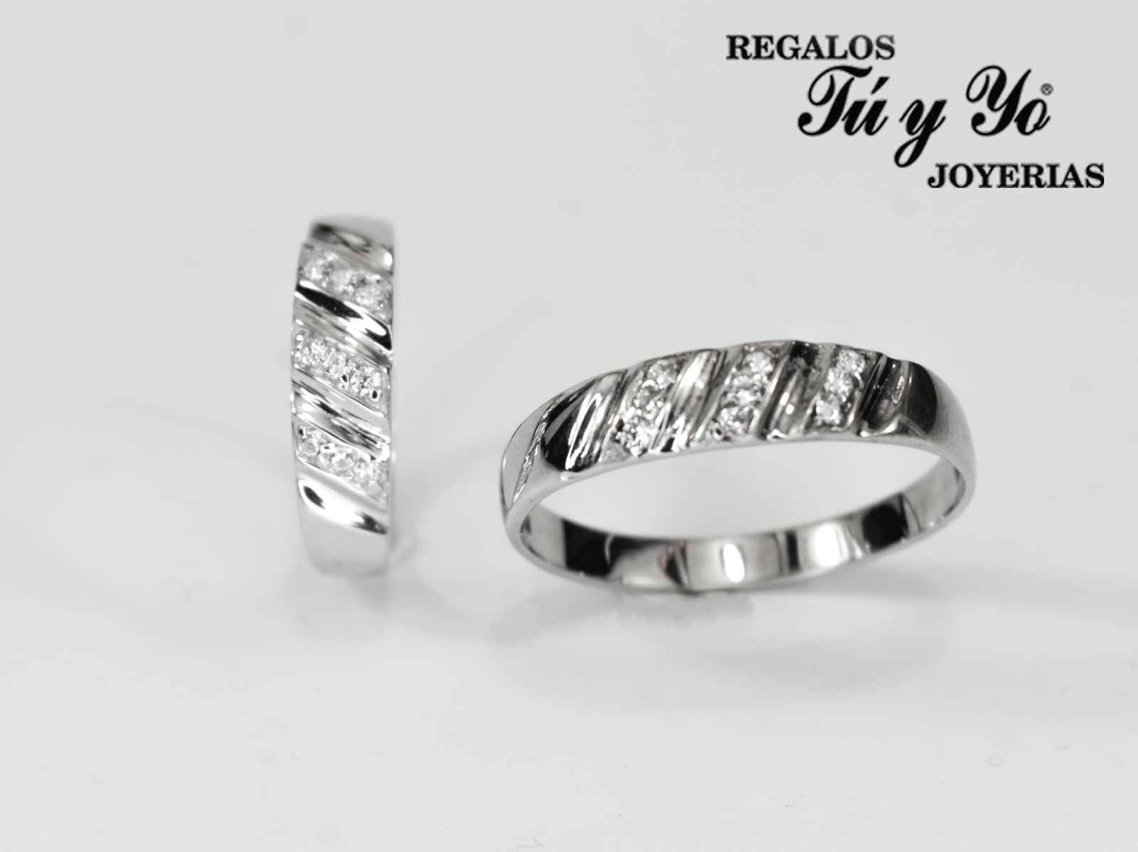 Two silver rings with diagonal diamond accents, branding 'Regalos Tú y Yo Joyerías' on white background.