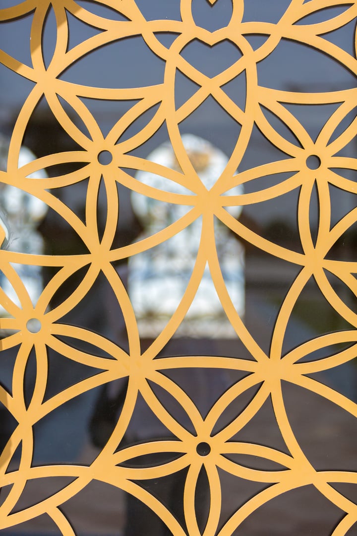 Golden geometric pattern of overlapping circles and lines against a blurred background.
