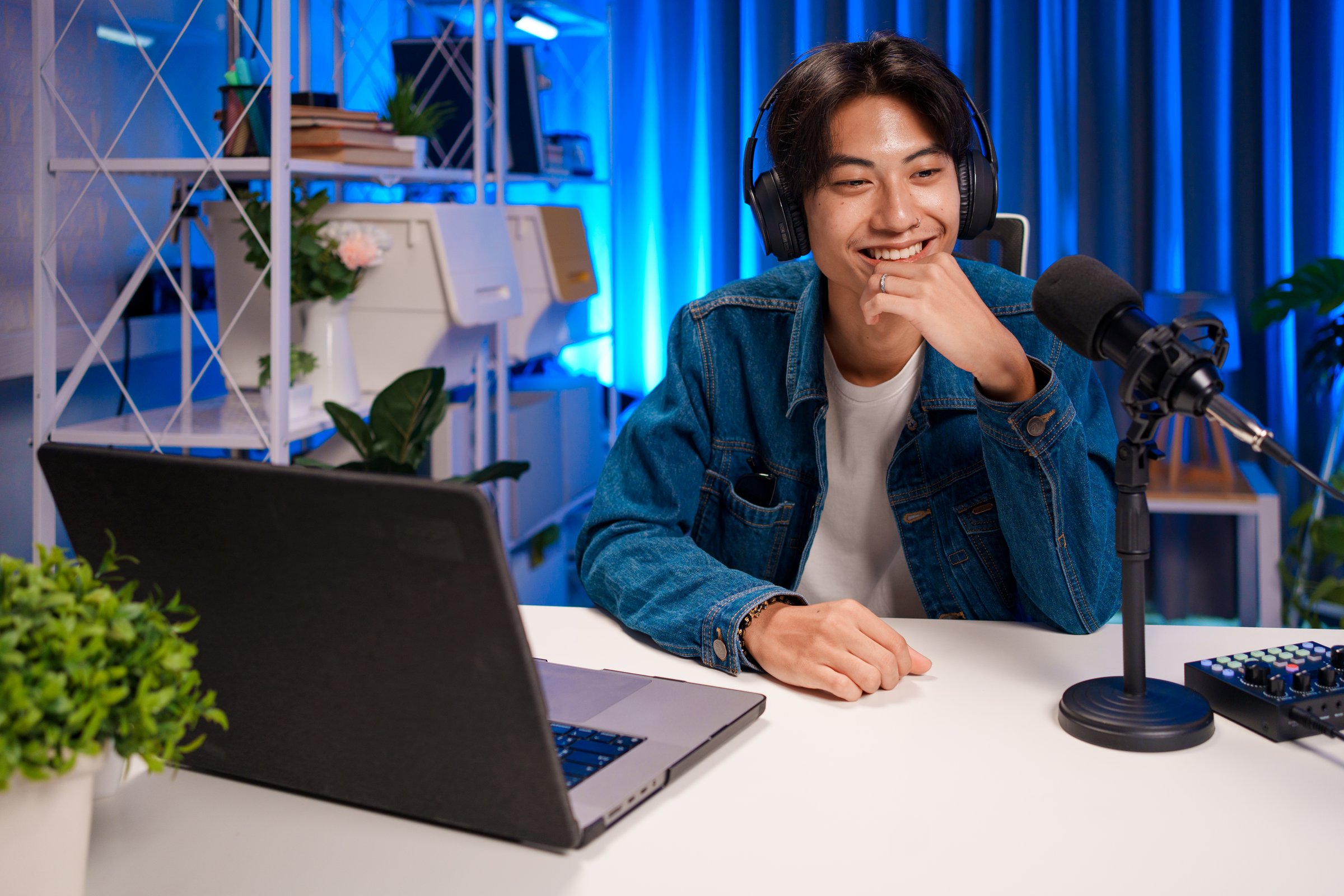 Young man smiling with headphones and microphone during a virtual podcast session