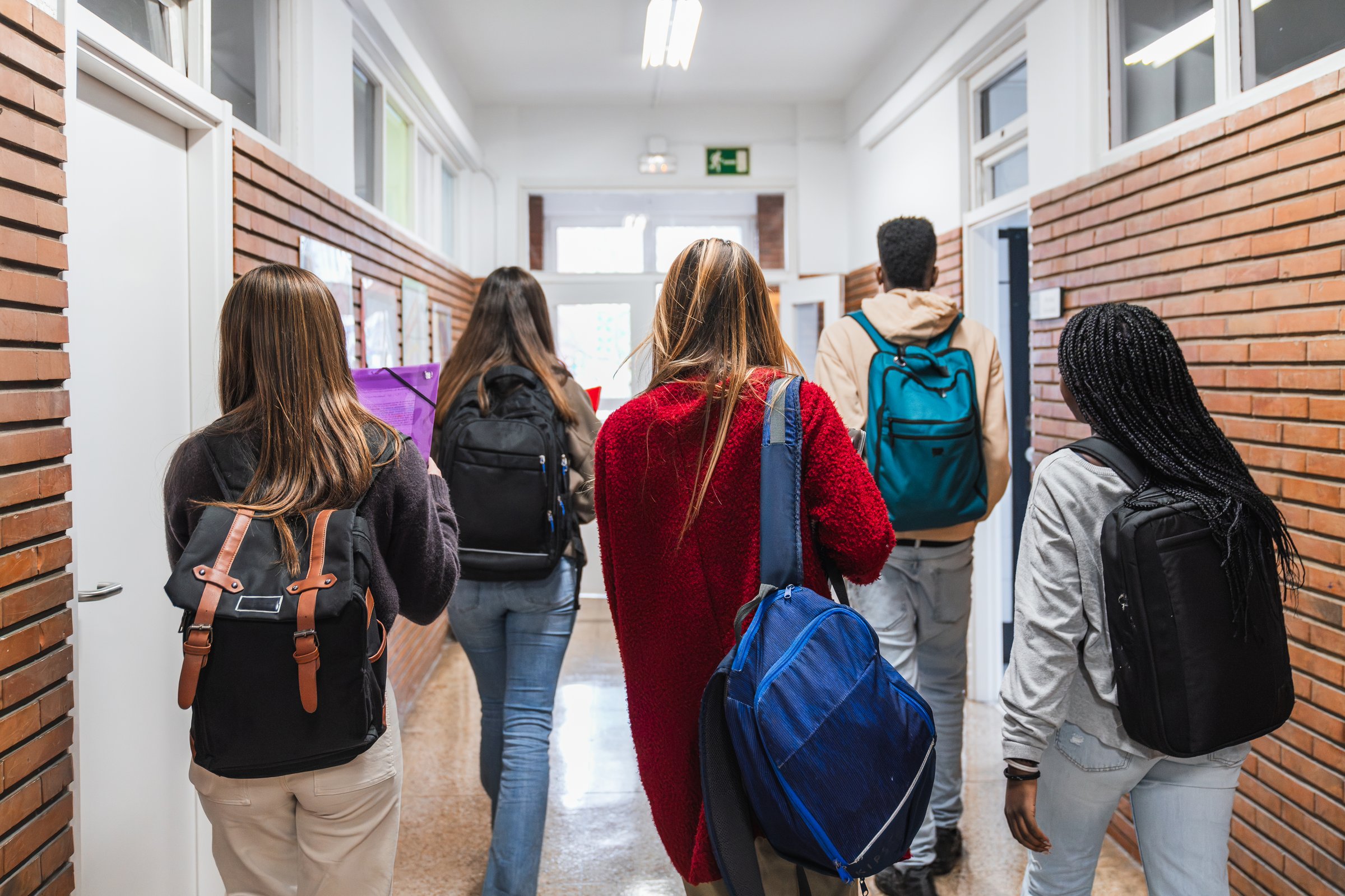 Diverse high school students walking together down a bustling school hallway, chatting and carrying backpacks, embodying youthful energy and camaraderie
