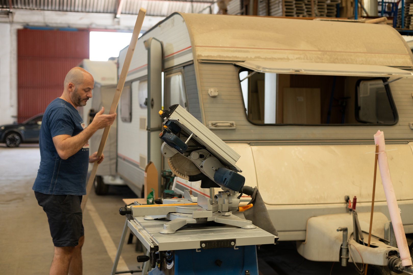 A young man works on the renovation of an old caravan, transforming it into a modern camper van. Concept of freedom, nomadic lifestyle, travel, and outdoor adventure. DIY and craftsmanship project, sustainable living, and creative mobile home renovation.