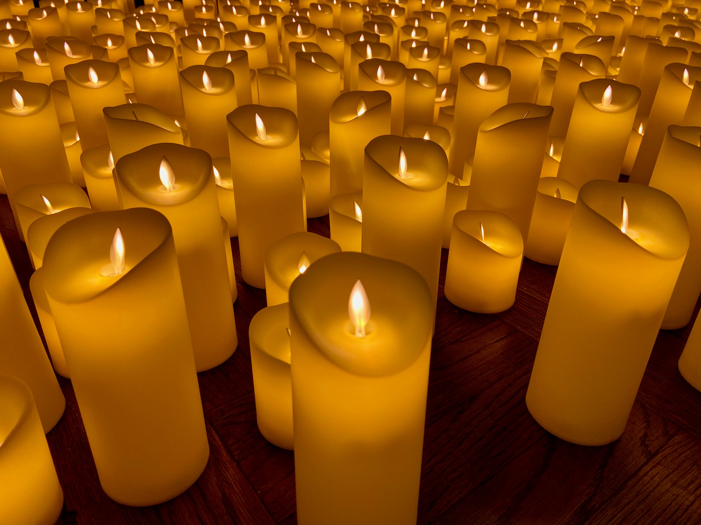 Close-up of hundreds of tall artificial candles glowing on the floor of a church for a holiday candlelight concert in New York City