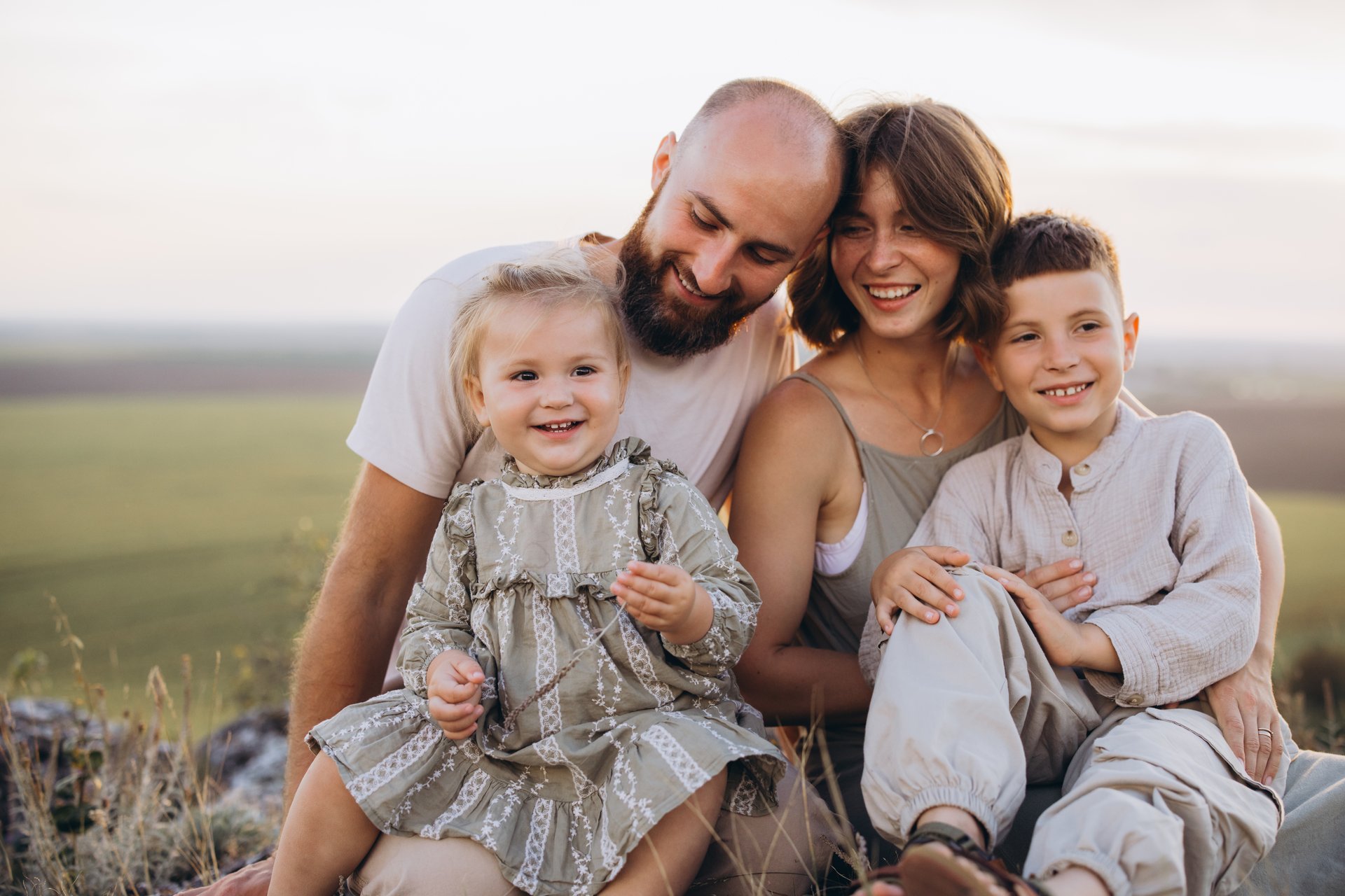 A joyful family with parents and young children spending time together. Captured outdoors in a tranquil field, showcasing happiness and love.