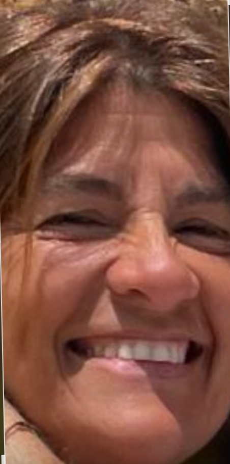 Close-up of a person smiling broadly, with sunlight illuminating their face and hair.