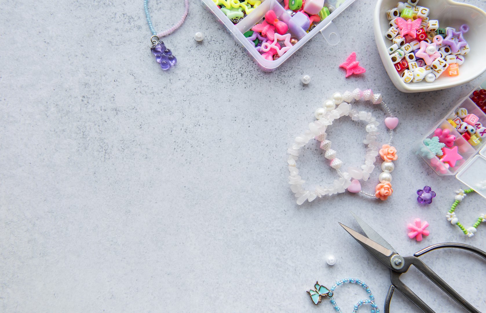 Bead crafting activity shows various colorful beads and tools spread on a gray surface, perfect for creating unique jewelry pieces in the afternoon light.