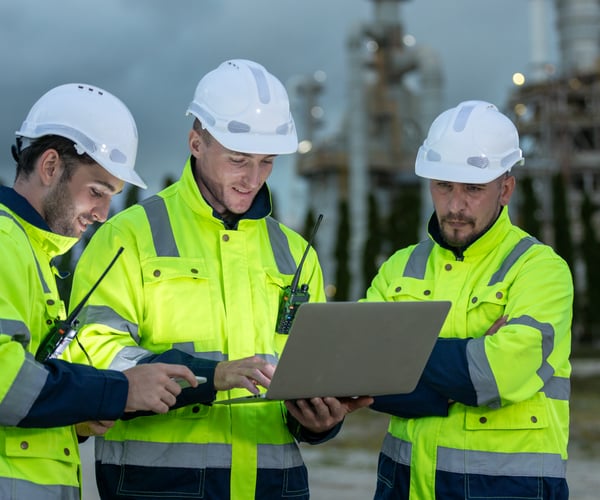 Team professional electrical engineer safety uniform working together power plant or station refining oil petrochemical using laptop evening. Industrial factory site control energy power station.