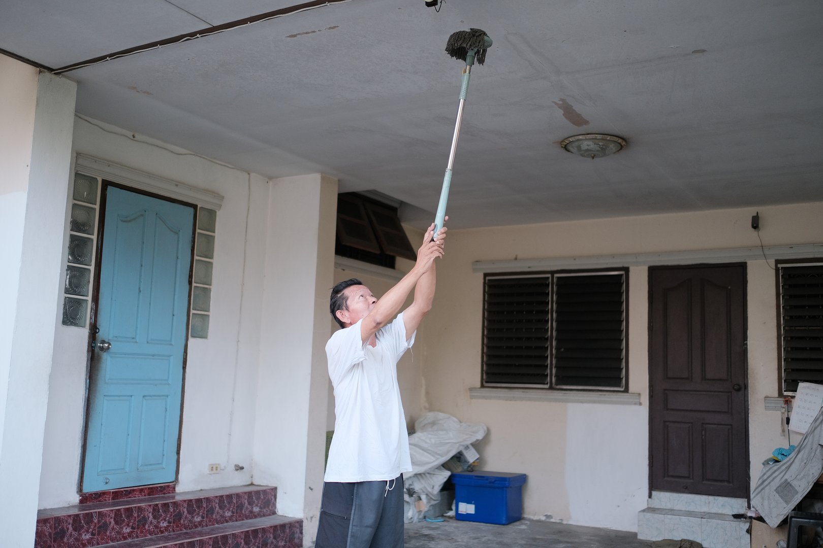 A man is painting a wall with a brush. Scene is calm and focused