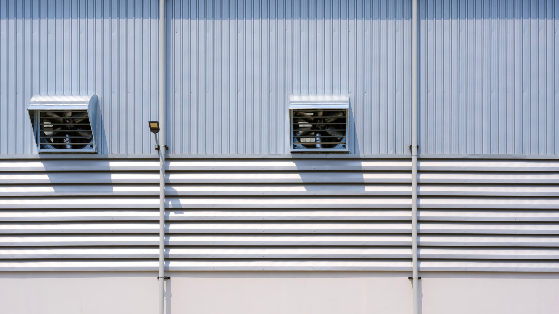 Industrial warehouse building background with ventilation fan and aluminum louver on corrugated metal wall