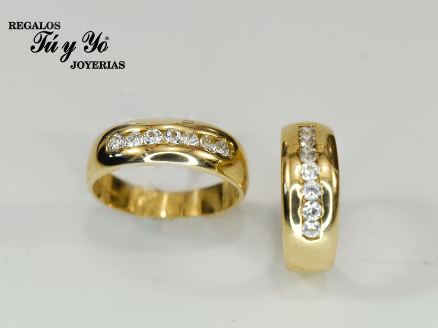 Two gold rings with embedded diamonds, displayed side by side on a plain background, with "Regalos Tú y Yo" text in the corner.