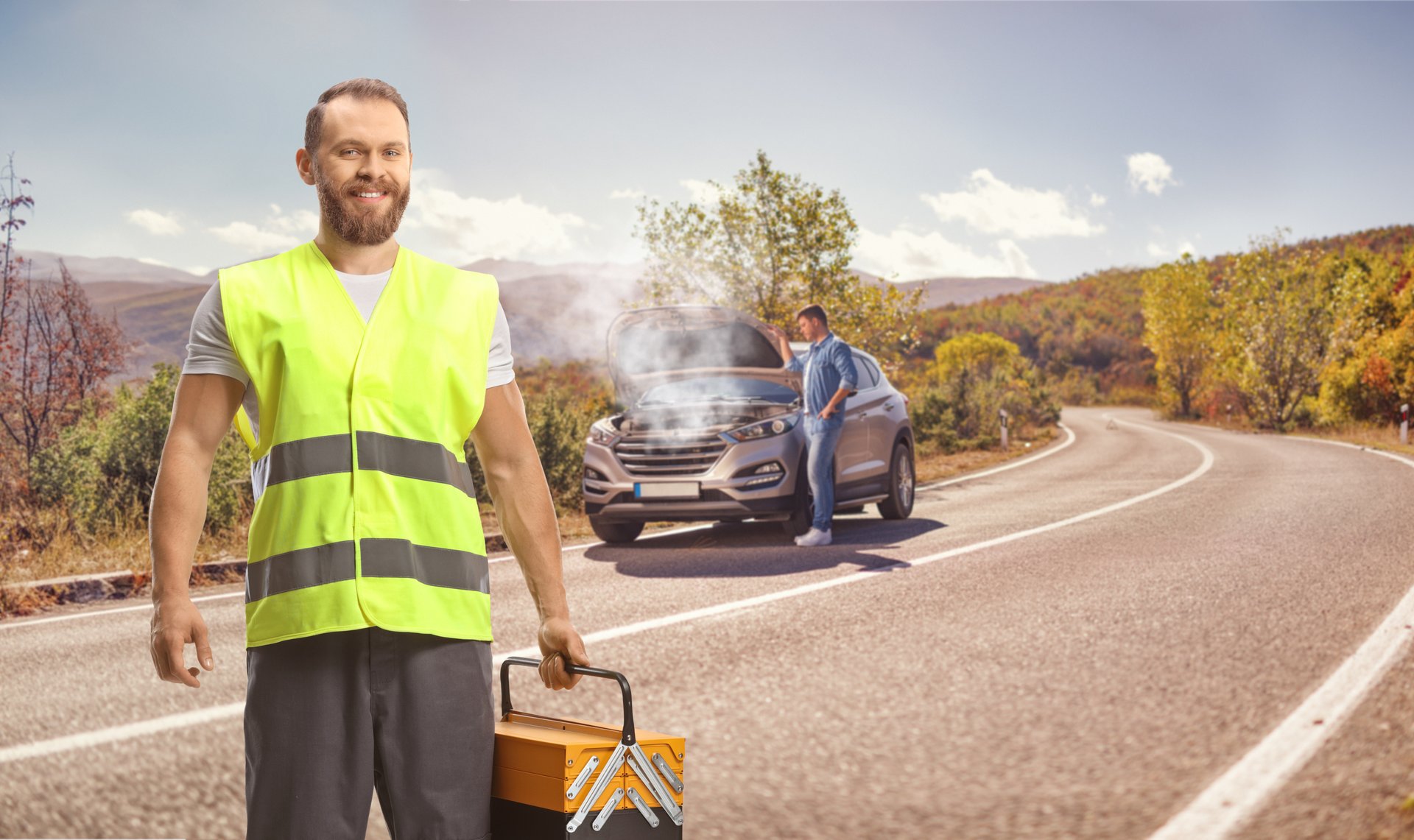 Man with a car breakdown on the road and a road help worker holding a tool box and smiling